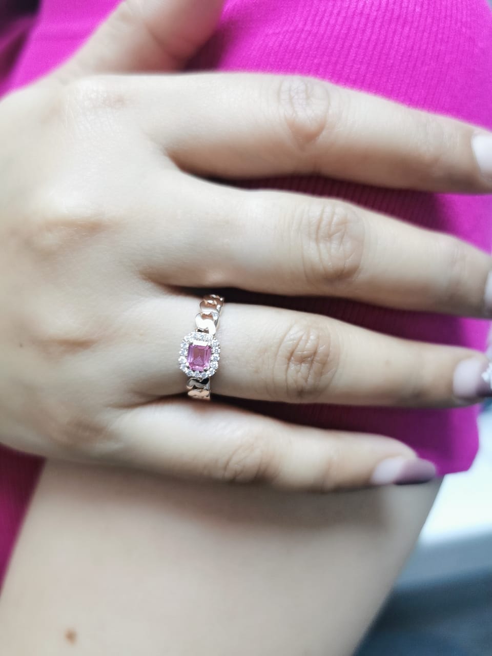 Elegant 18K gold pink sapphire and diamond halo ring with a 0.50-carat emerald-cut pink sapphire, surrounded by 0.14-carat round diamonds and a chain-link band design.