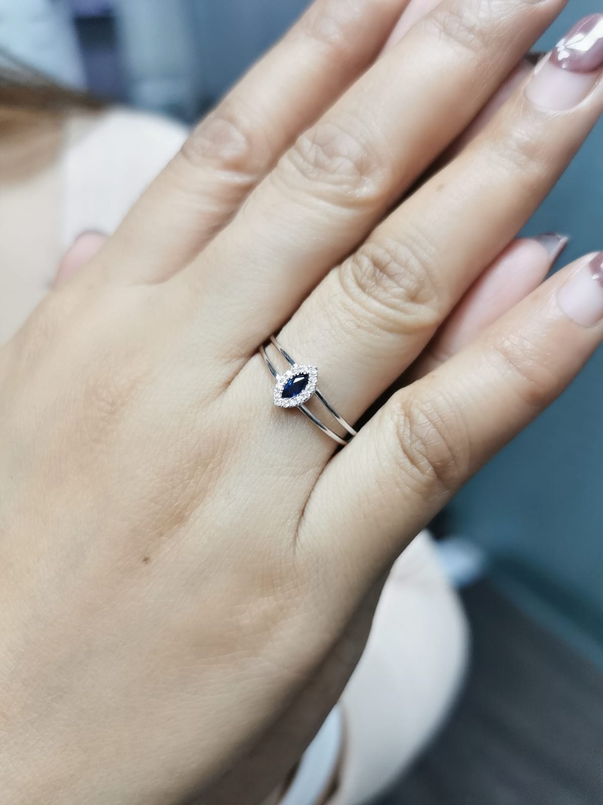 18K gold marquise-cut blue sapphire and diamond halo ring featuring a 0.16-carat blue sapphire, framed by 0.05 carats of diamonds, set in an elegant double-band design.