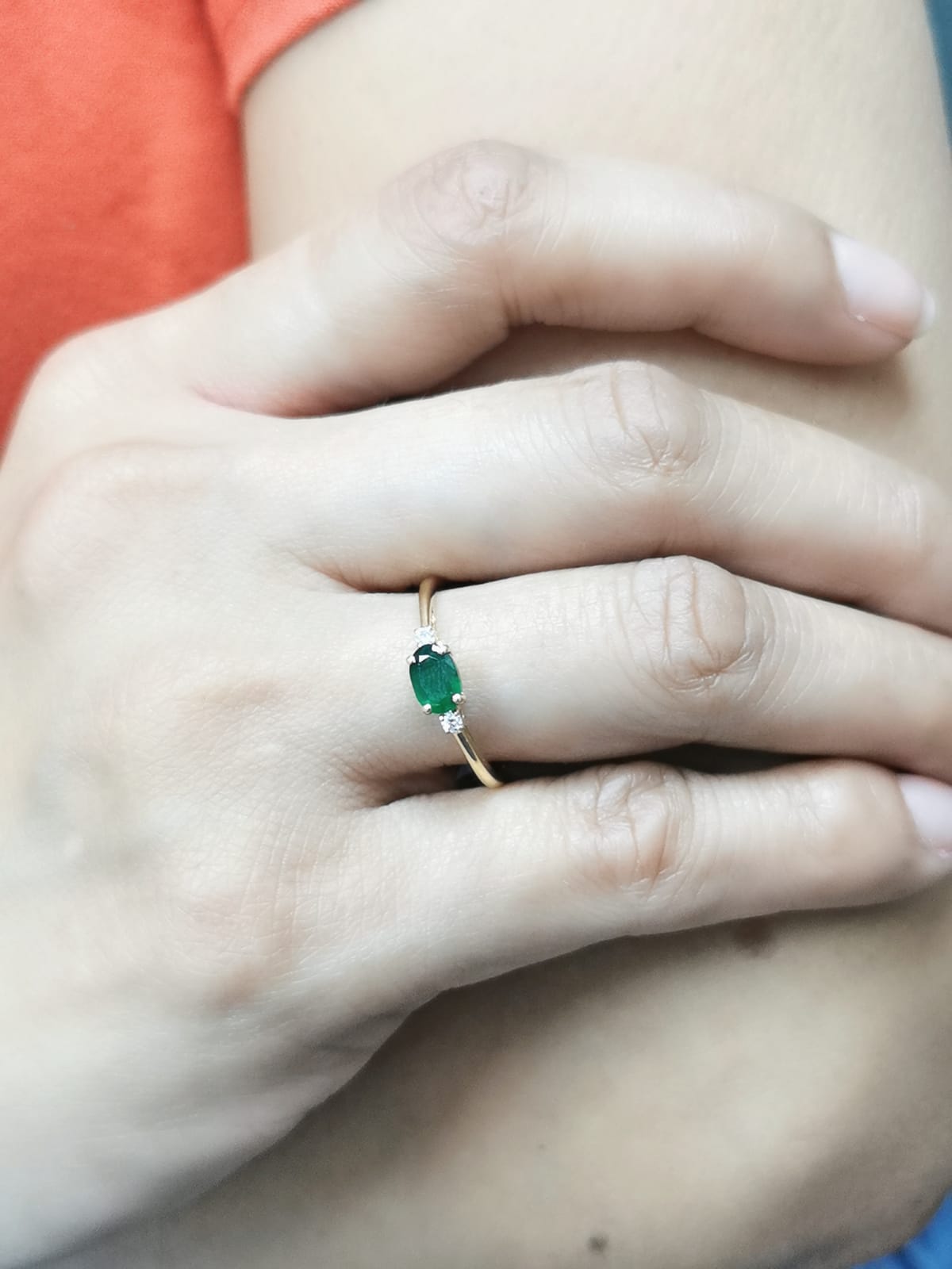 18K yellow gold oval emerald and diamond ring featuring a 0.59-carat emerald with 0.05-carat round diamonds on each side in a classic four-prong setting.
