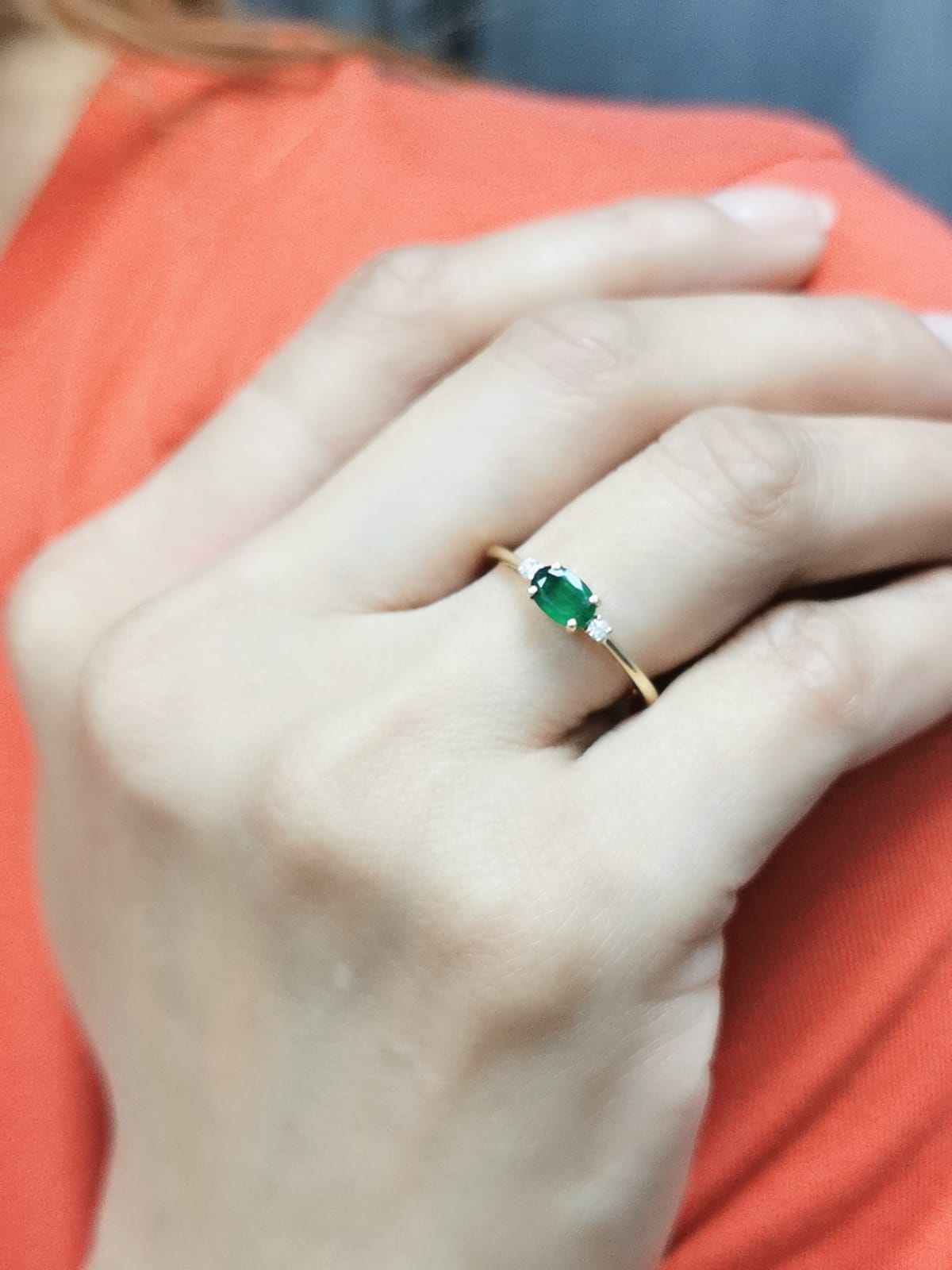 18K yellow gold oval emerald and diamond ring featuring a 0.59-carat emerald with 0.05-carat round diamonds on each side in a classic four-prong setting.