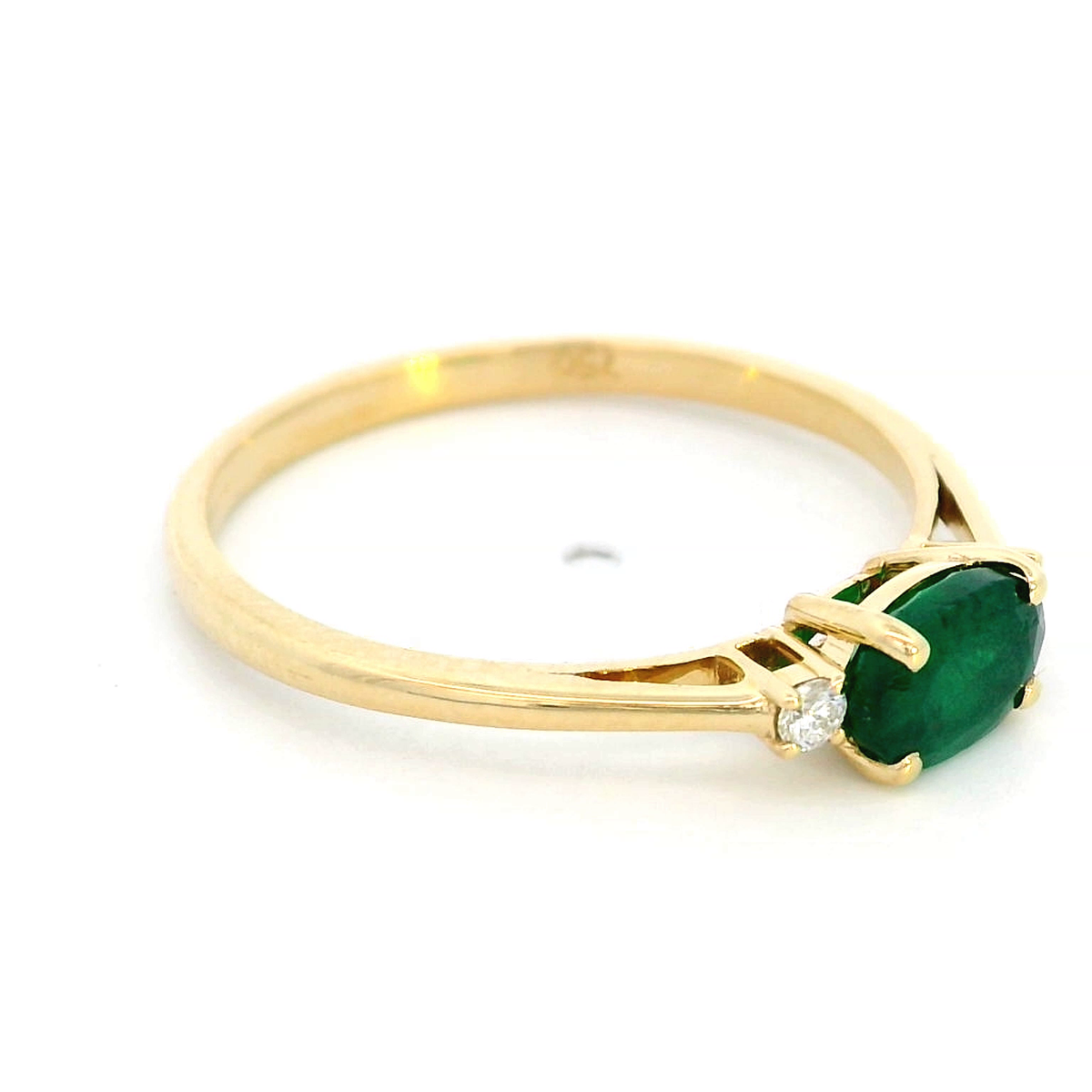 18K yellow gold oval emerald and diamond ring featuring a 0.59-carat emerald with 0.05-carat round diamonds on each side in a classic four-prong setting.