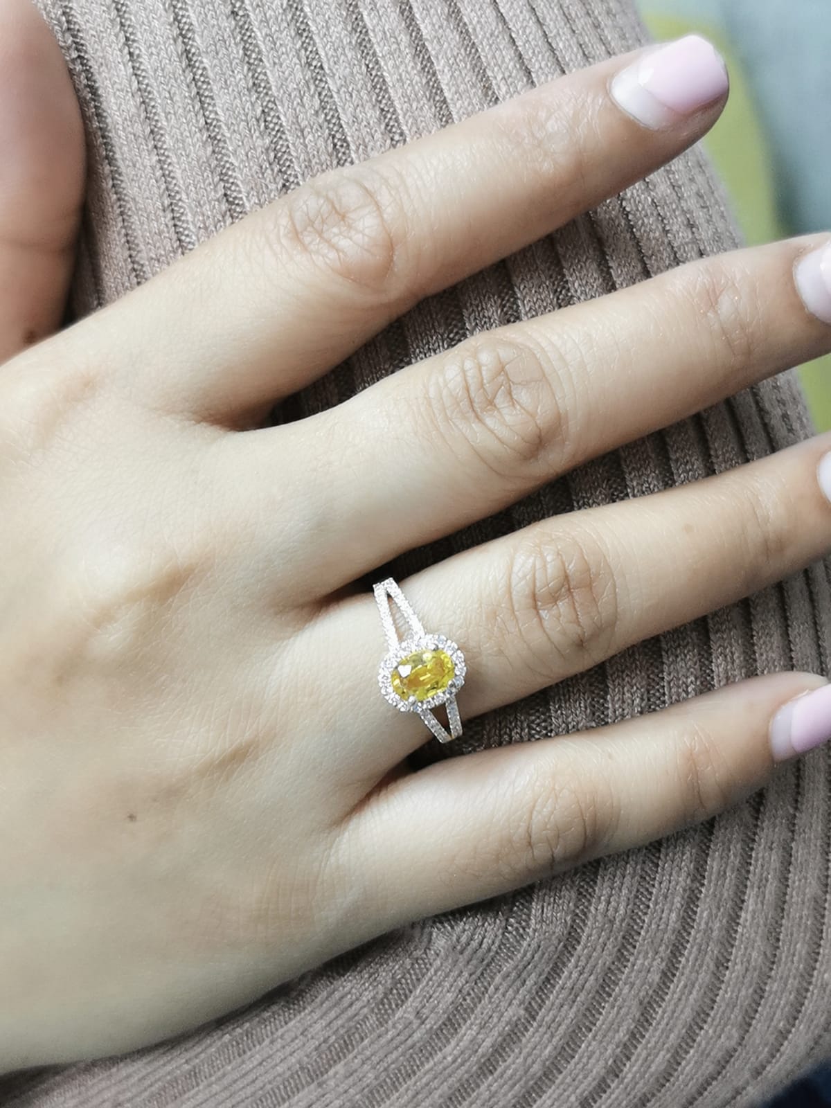 Yellow sapphire and diamond halo ring in 18K yellow gold featuring a 1.21-carat oval yellow sapphire, surrounded by a diamond halo and a split band adorned with diamonds, totaling 0.35 carats, with a smooth polished gold finish