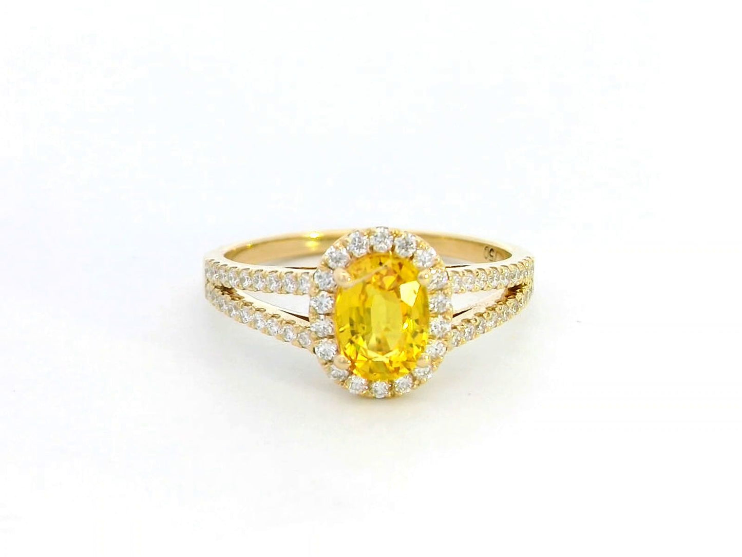 Yellow sapphire and diamond halo ring in 18K yellow gold featuring a 1.21-carat oval yellow sapphire, surrounded by a diamond halo and a split band adorned with diamonds, totaling 0.35 carats, with a smooth polished gold finish