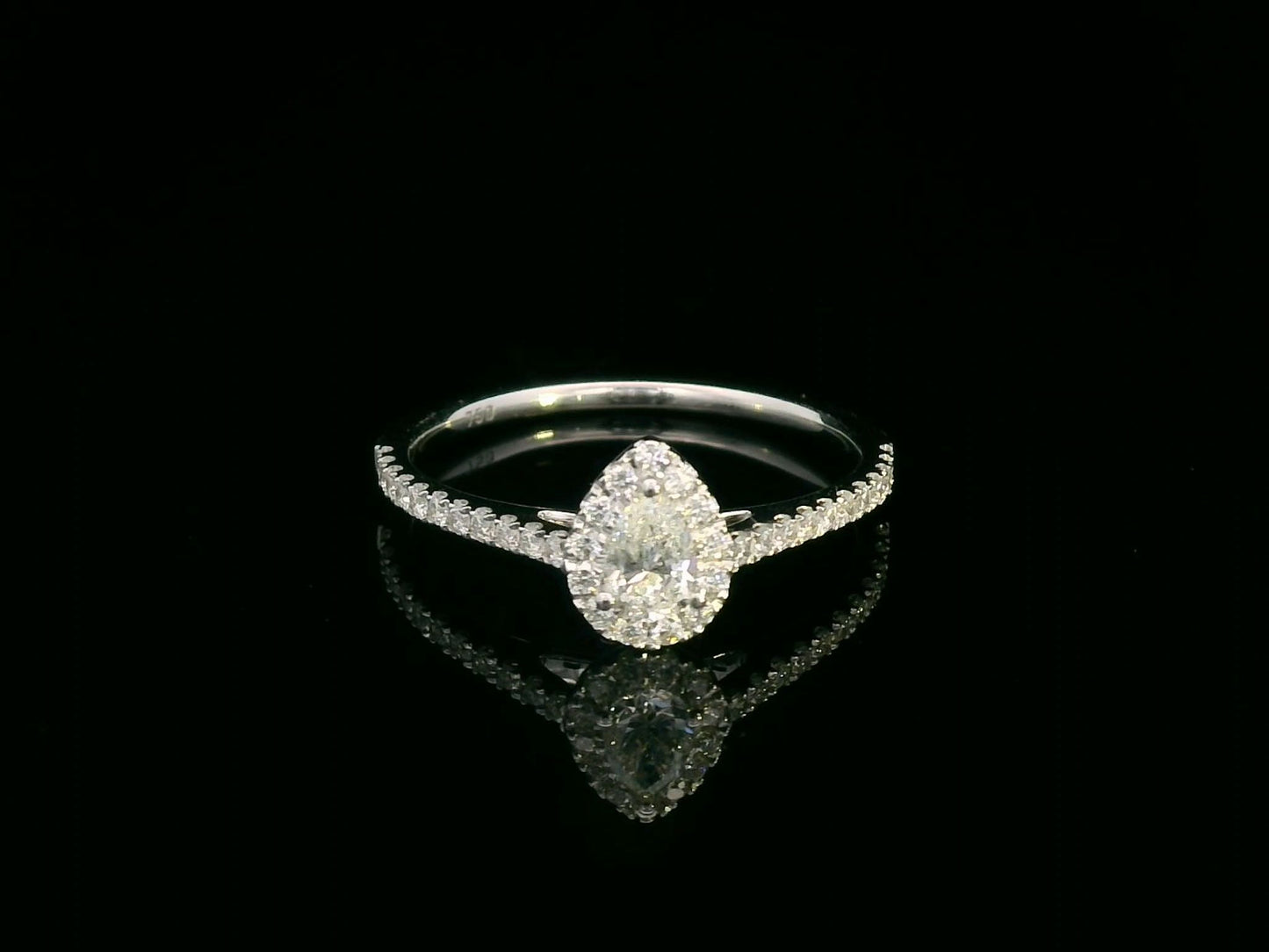 18K gold pear-cut diamond halo ring with a 0.25ct center stone and accent diamonds on a delicate band.