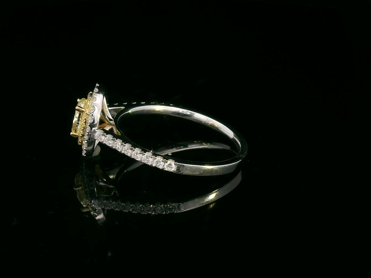 Oval fancy yellow diamond engagement ring in 18K white gold with a yellow diamond inner halo, white diamond outer halo and diamond-set band.
