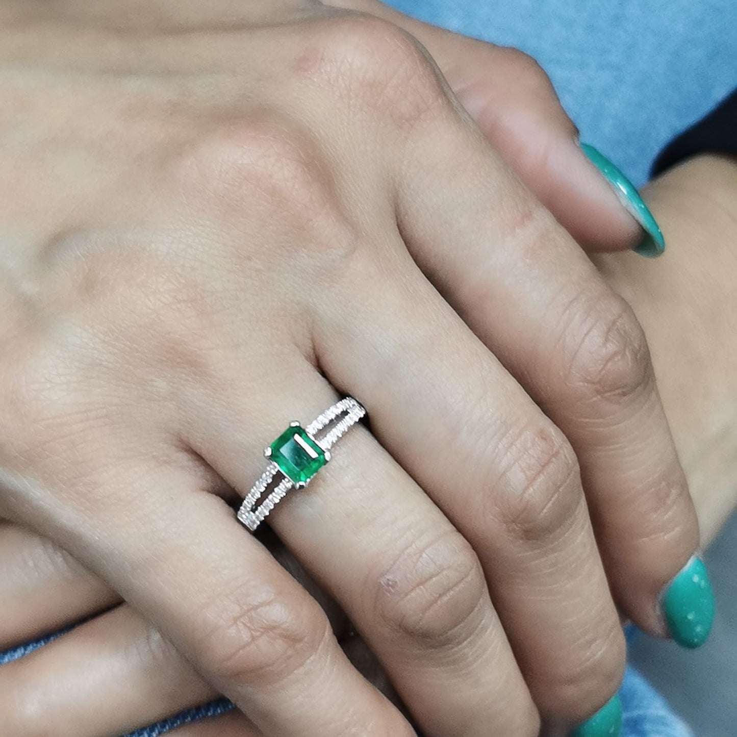 18K white gold emerald ring featuring a 0.78-carat emerald-cut green emerald with 0.25-carat diamond accents on a split band.
