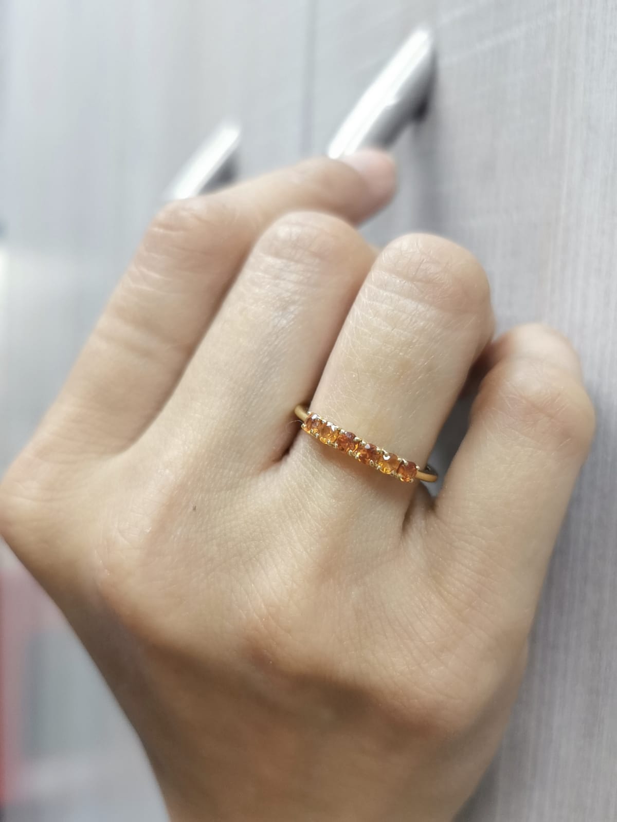 18K yellow gold ring with six round-cut orange sapphires in a half eternity setting