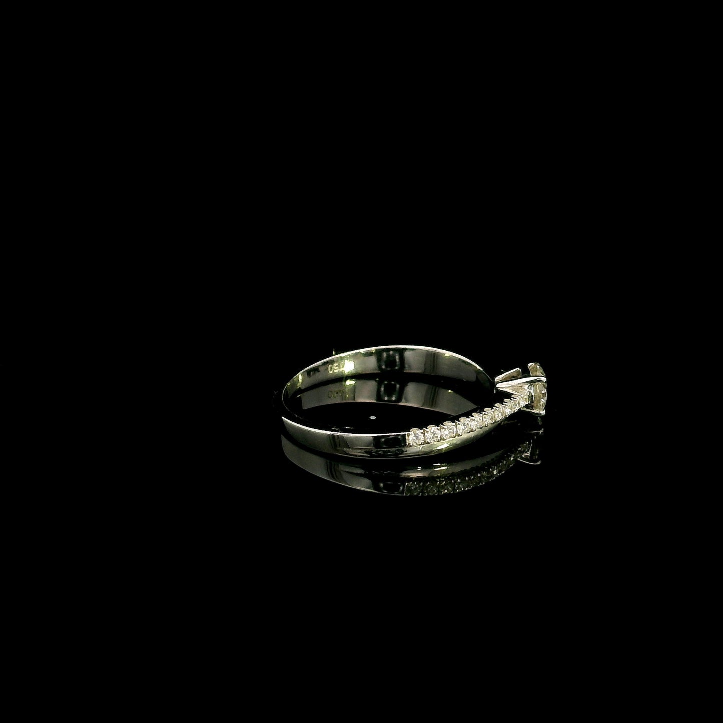 18K white gold minimalist engagement ring featuring a round brilliant diamond with an asymmetrical crossover band and pavé diamonds.