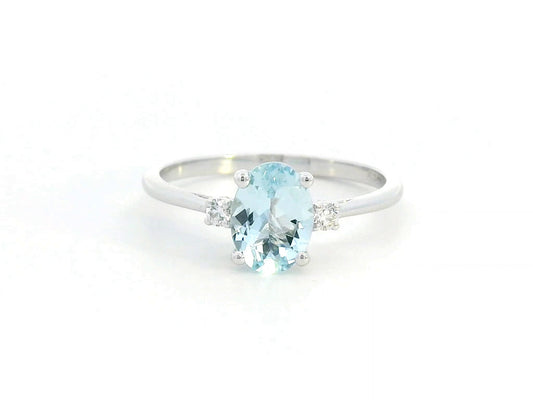 Oval Aquamarine and diamond ring in 18K gold, featuring a 0.93ct blue gemstone flanked by round-cut diamonds.
