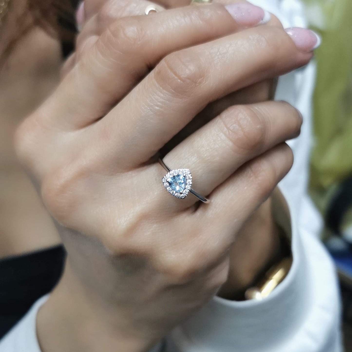 Trillion-cut aquamarine and diamond halo ring in 18K white gold, featuring a 0.50-carat aquamarine center stone surrounded by 0.15-carat diamonds.