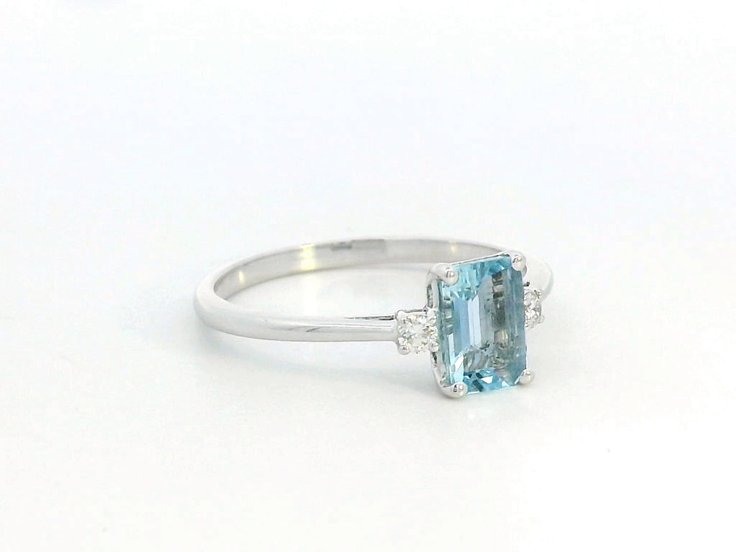 18K white gold aquamarine and diamond ring featuring a 0.65-carat emerald-cut aquamarine with 0.07-carat round diamonds in a minimalist fine jewelry design – perfect for engagements, gifts, and March birthstone jewelry.