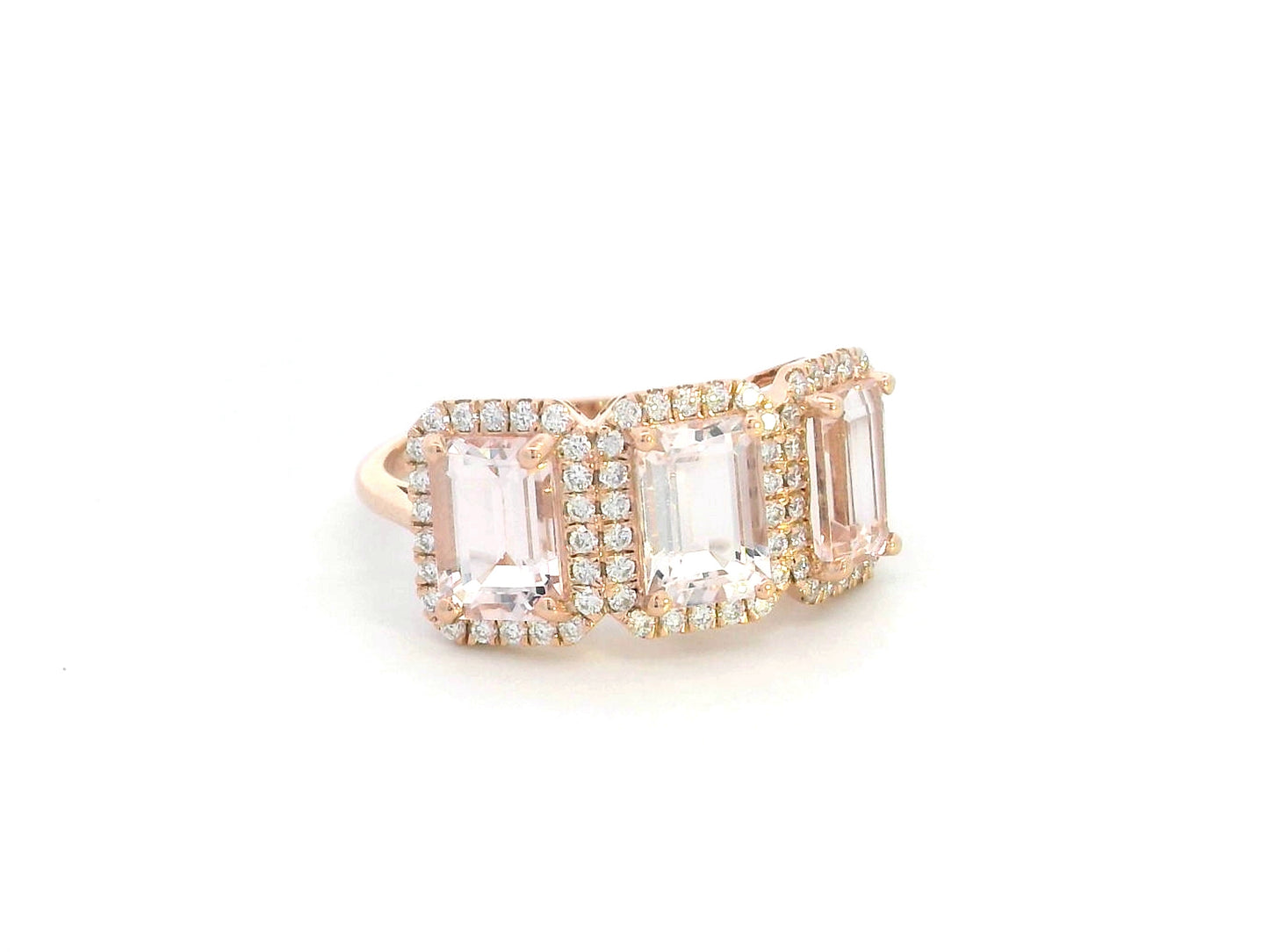 18K rose gold three-stone morganite and diamond ring featuring 2.79 carats of emerald-cut morganite with 0.38 carats of brilliant diamonds in a halo setting. A perfect statement or anniversary ring