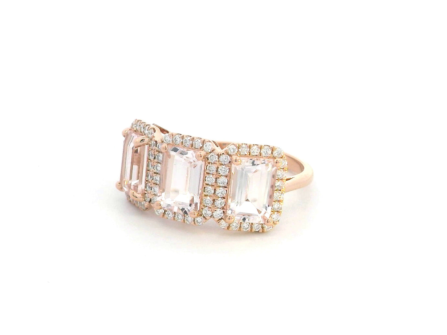 18K rose gold three-stone morganite and diamond ring featuring 2.79 carats of emerald-cut morganite with 0.38 carats of brilliant diamonds in a halo setting. A perfect statement or anniversary ring