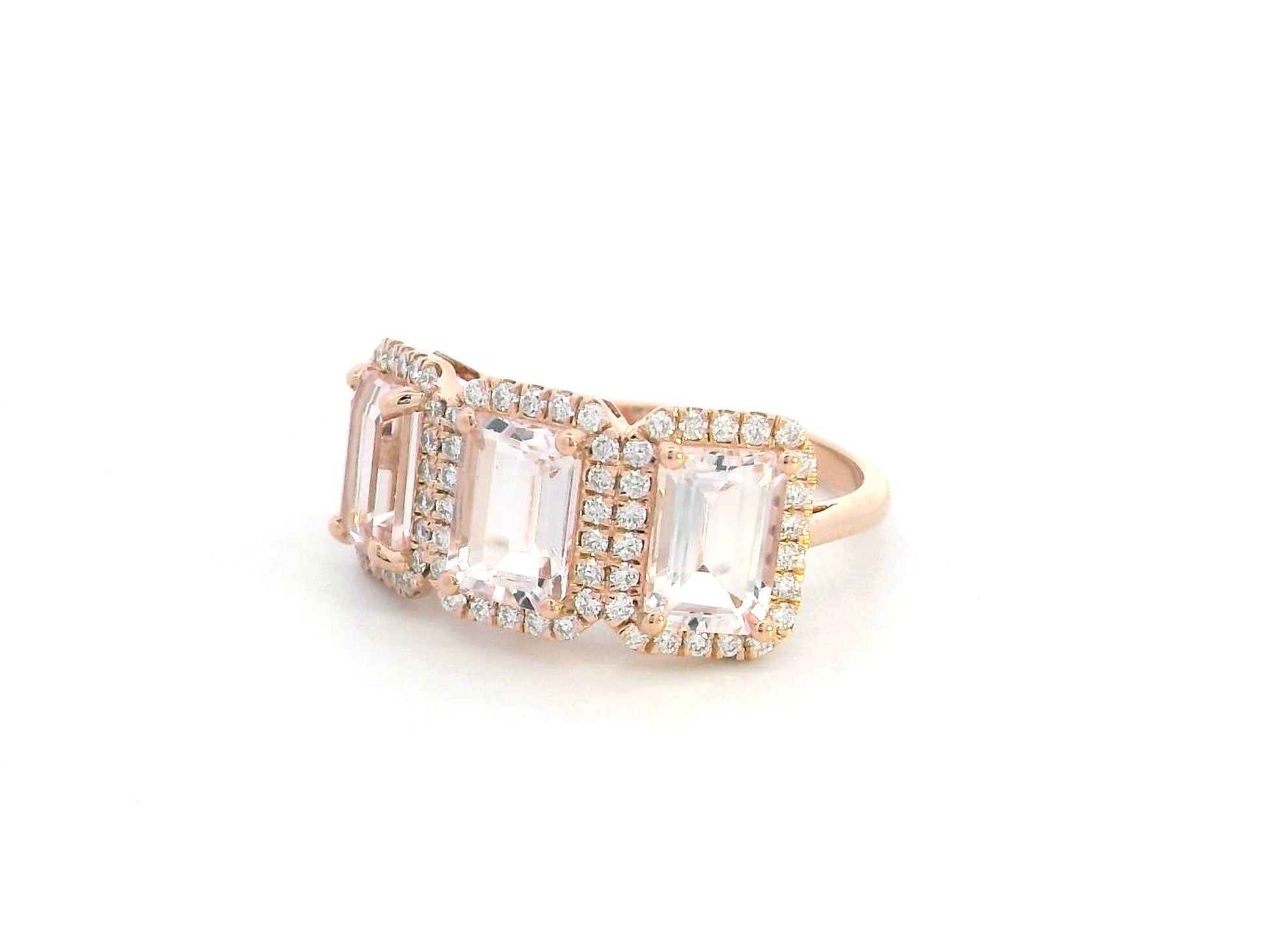 18K rose gold three-stone morganite and diamond ring featuring 2.79 carats of emerald-cut morganite with 0.38 carats of brilliant diamonds in a halo setting. A perfect statement or anniversary ring