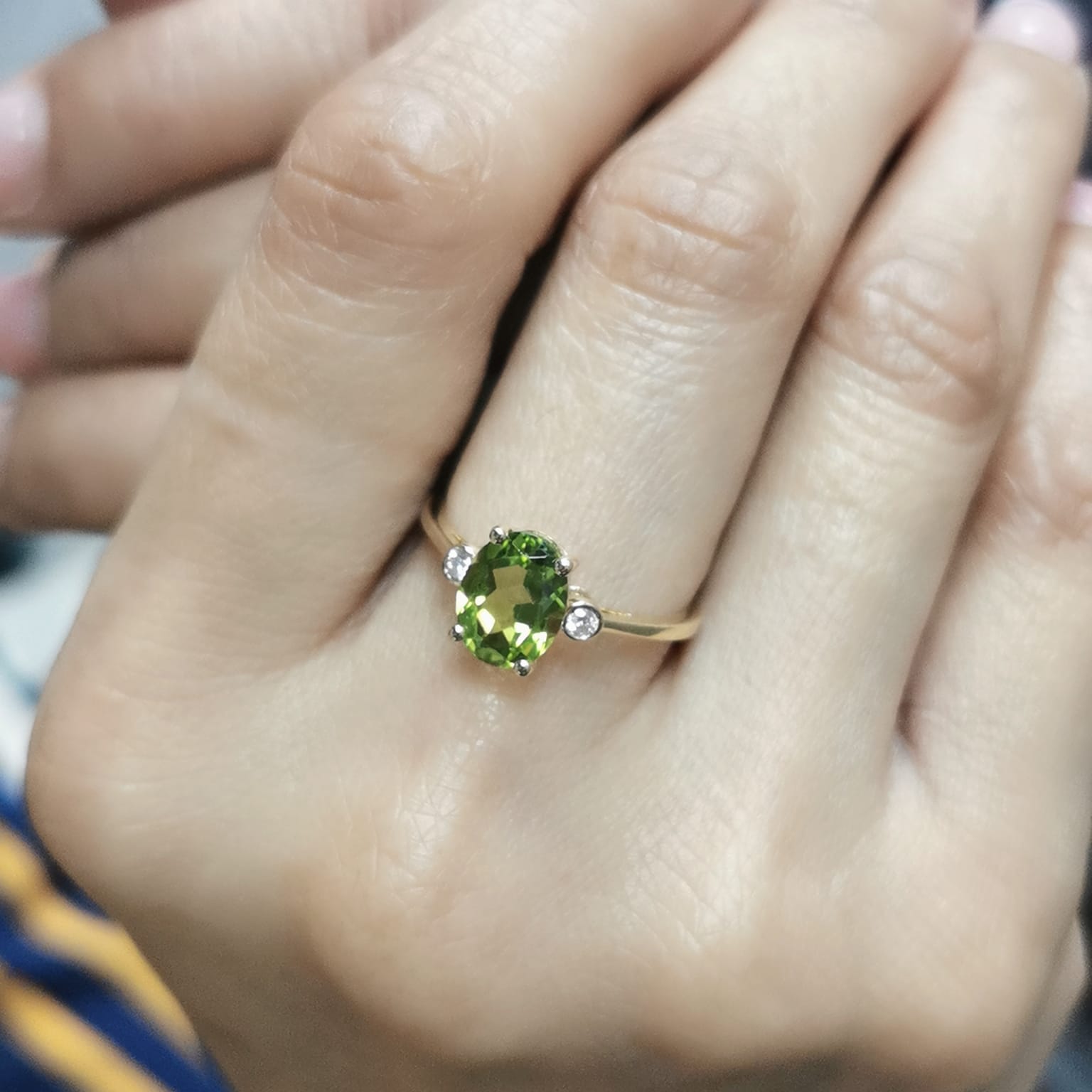 Oval peridot and diamond ring in 18K gold, featuring a 2.02-carat green peridot with 0.06-carat diamond accents.