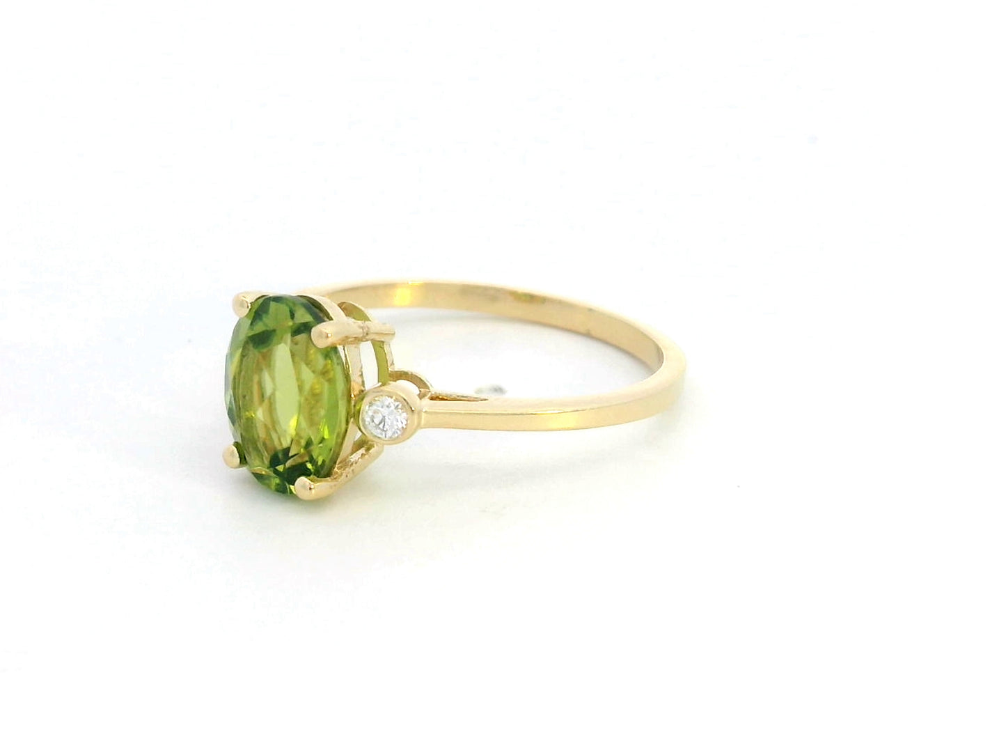 Oval peridot and diamond ring in 18K gold, featuring a 2.02-carat green peridot with 0.06-carat diamond accents.
