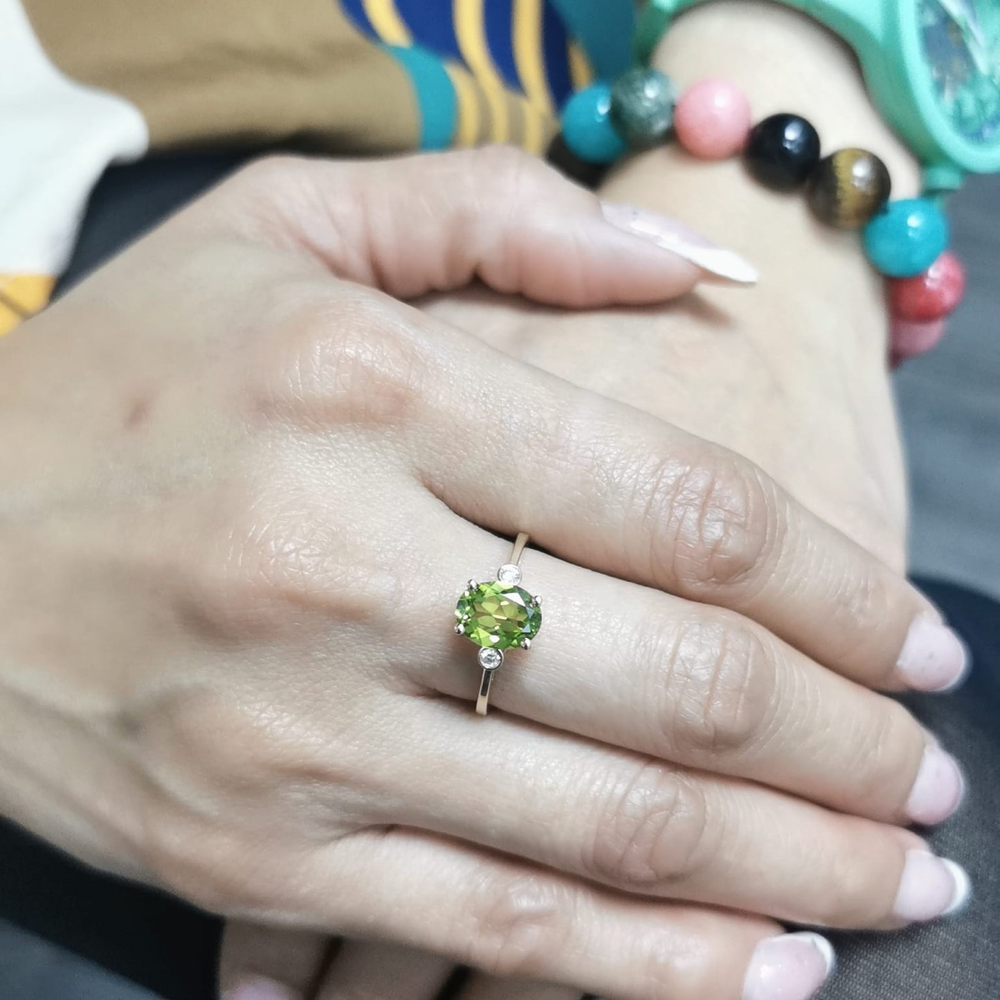 Oval peridot and diamond ring in 18K gold, featuring a 2.02-carat green peridot with 0.06-carat diamond accents.
