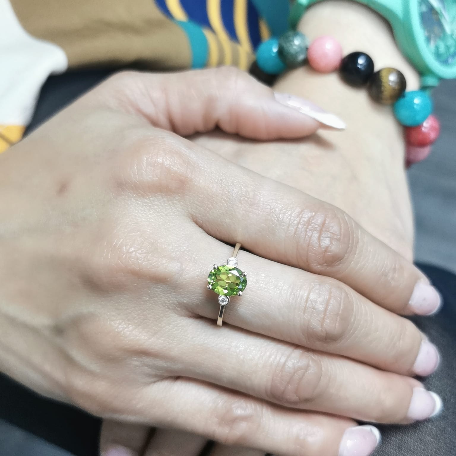 Oval peridot and diamond ring in 18K gold, featuring a 2.02-carat green peridot with 0.06-carat diamond accents.