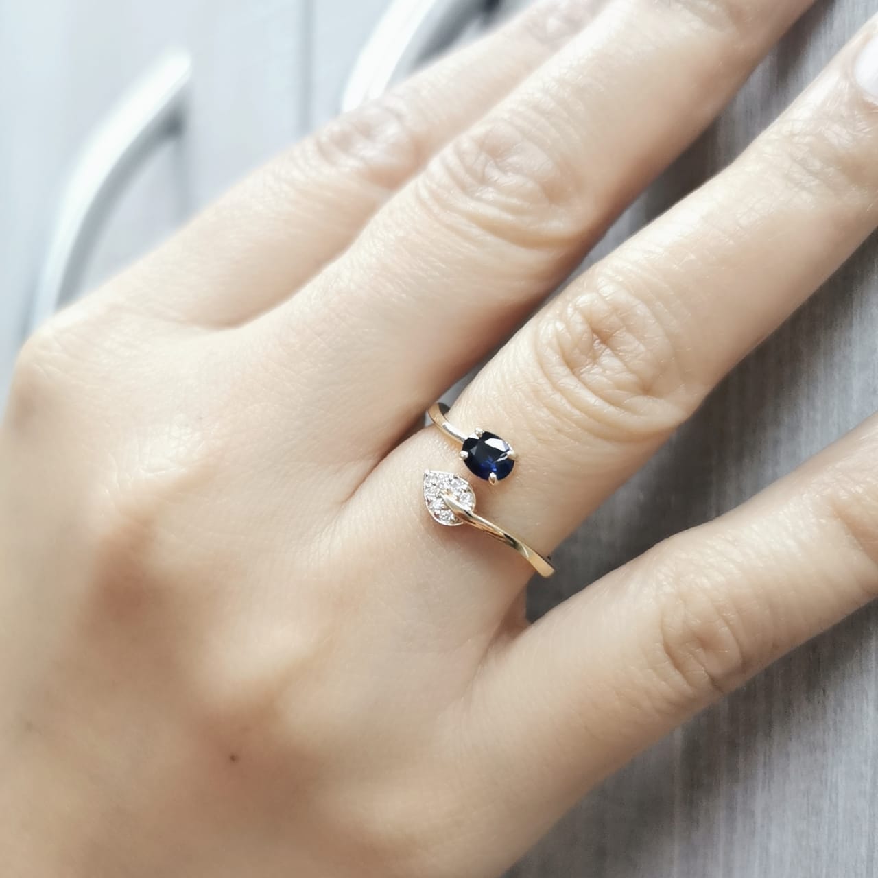18K yellow gold sapphire and diamond ring featuring a 0.45-carat blue sapphire and 0.06-carat diamonds in an elegant bypass design