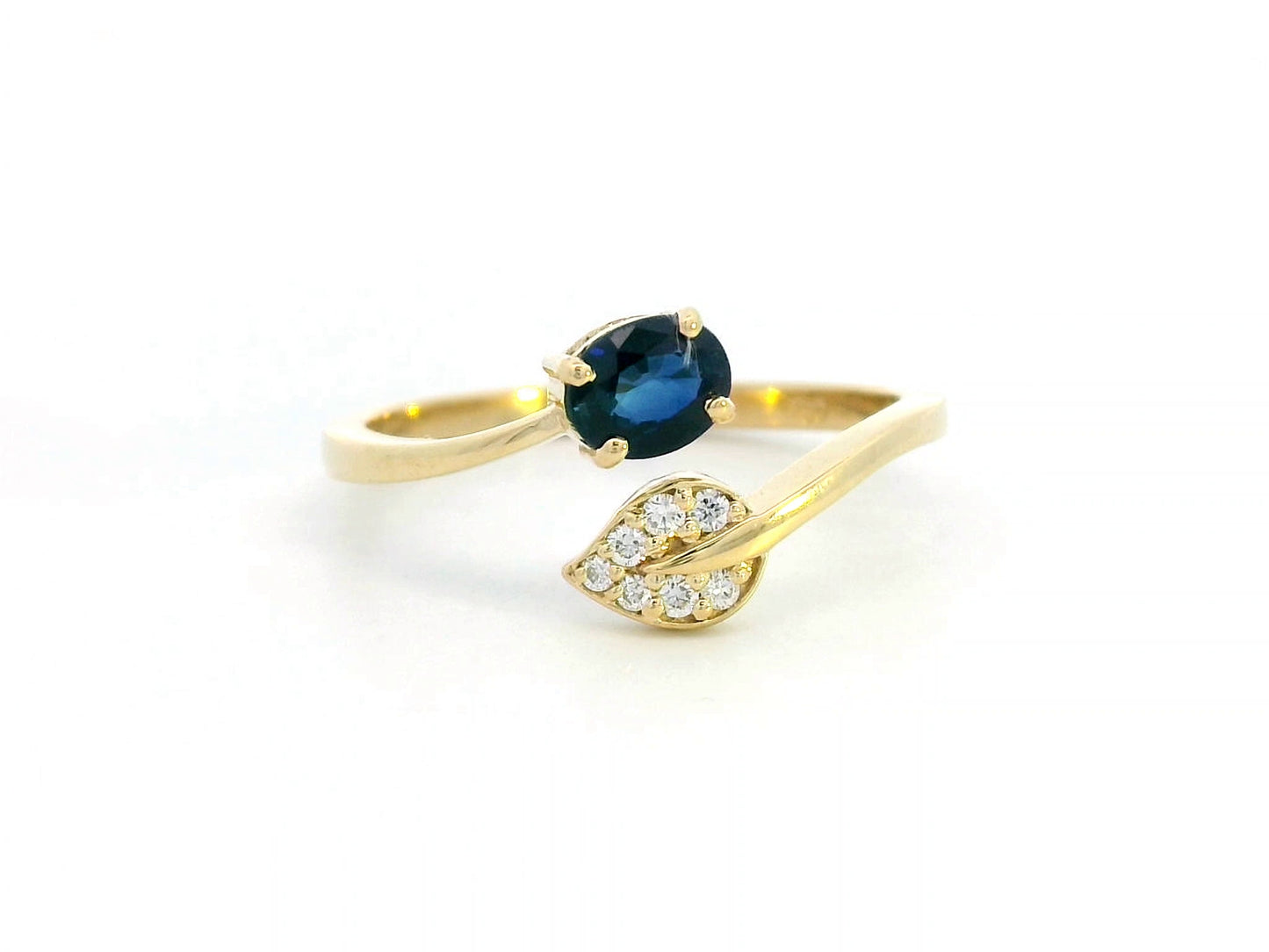 18K yellow gold sapphire and diamond ring featuring a 0.45-carat blue sapphire and 0.06-carat diamonds in an elegant bypass design