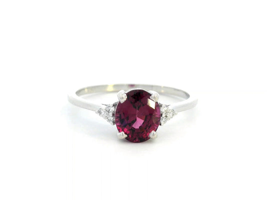 18K white gold ring featuring a 1.71-carat oval rhodolite garnet with three round-cut diamond accents (0.06 CT total) on a polished band.