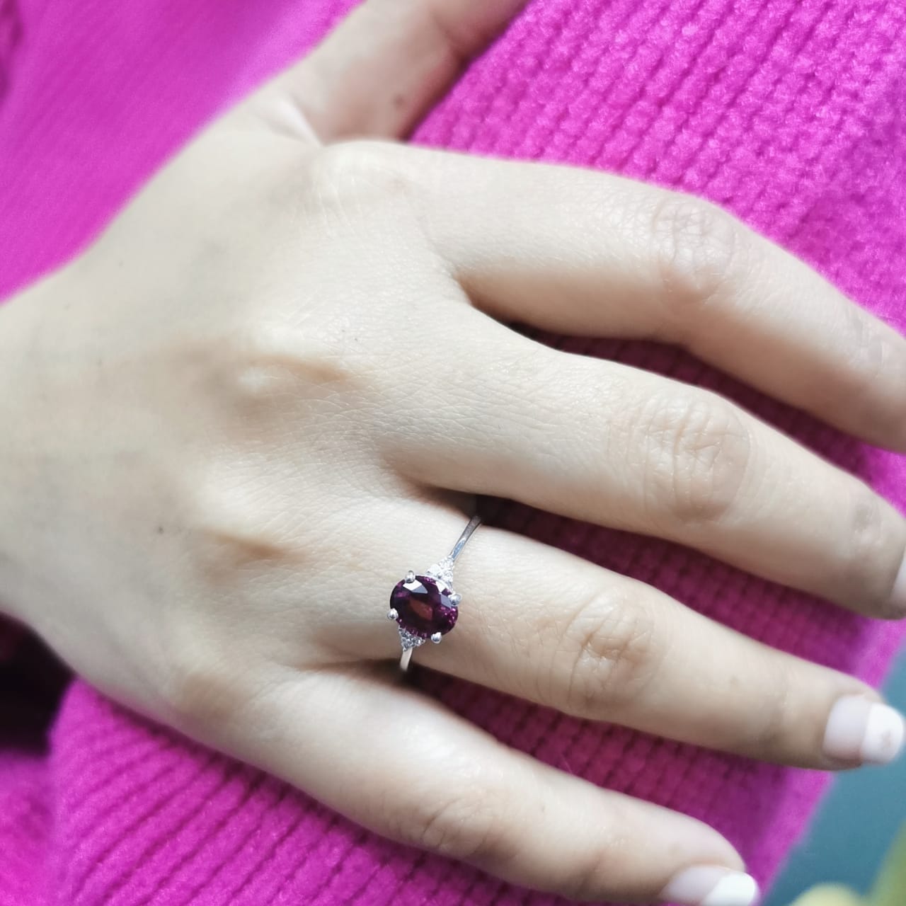 18K white gold ring featuring a 1.71-carat oval rhodolite garnet with three round-cut diamond accents (0.06 CT total) on a polished band.