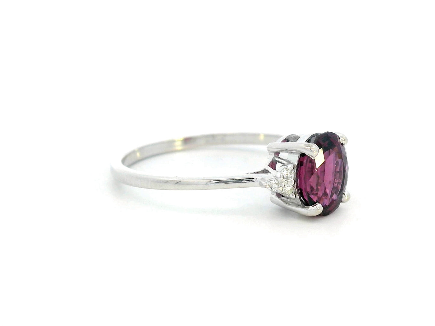 18K white gold ring featuring a 1.71-carat oval rhodolite garnet with three round-cut diamond accents (0.06 CT total) on a polished band.