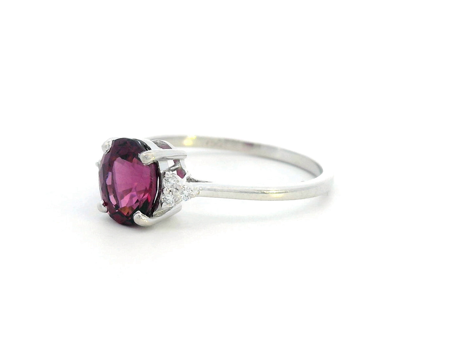 18K white gold ring featuring a 1.71-carat oval rhodolite garnet with three round-cut diamond accents (0.06 CT total) on a polished band.