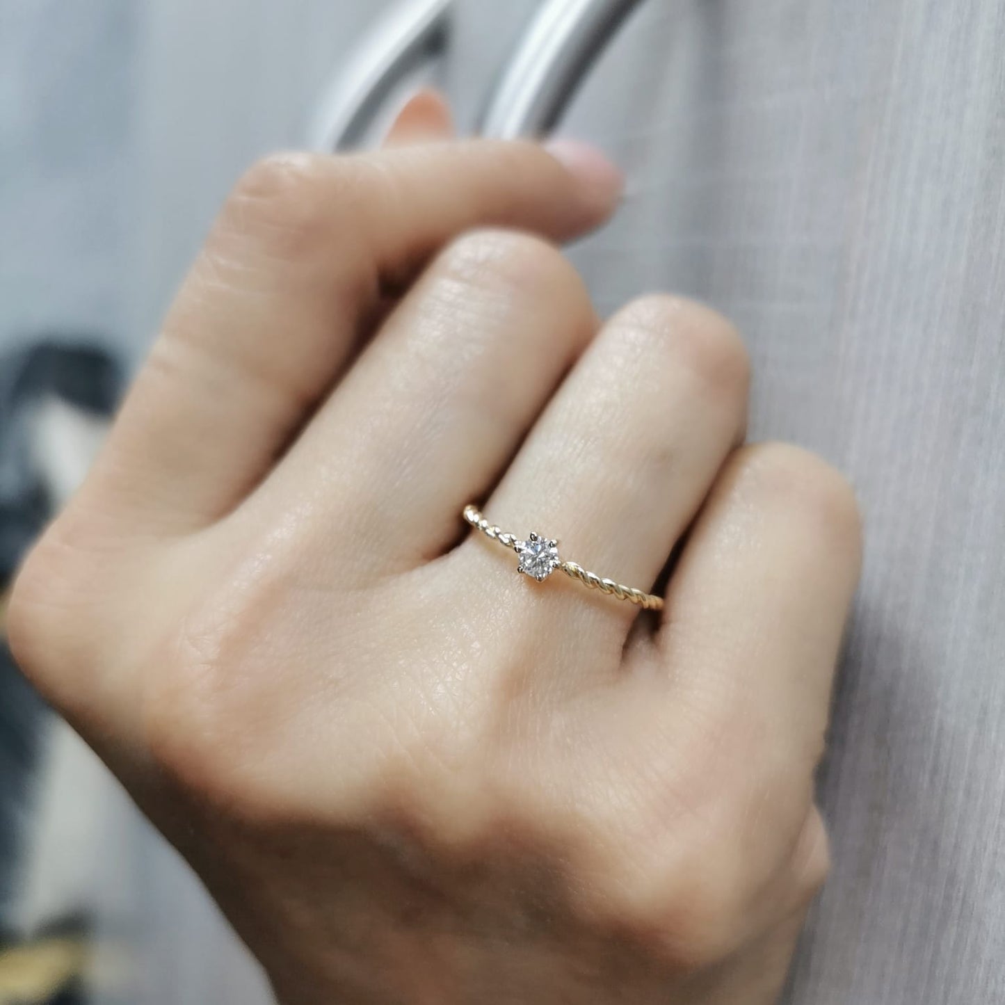 18K yellow gold twisted band diamond ring featuring a 0.15-carat round solitaire diamond in a delicate rope-style design