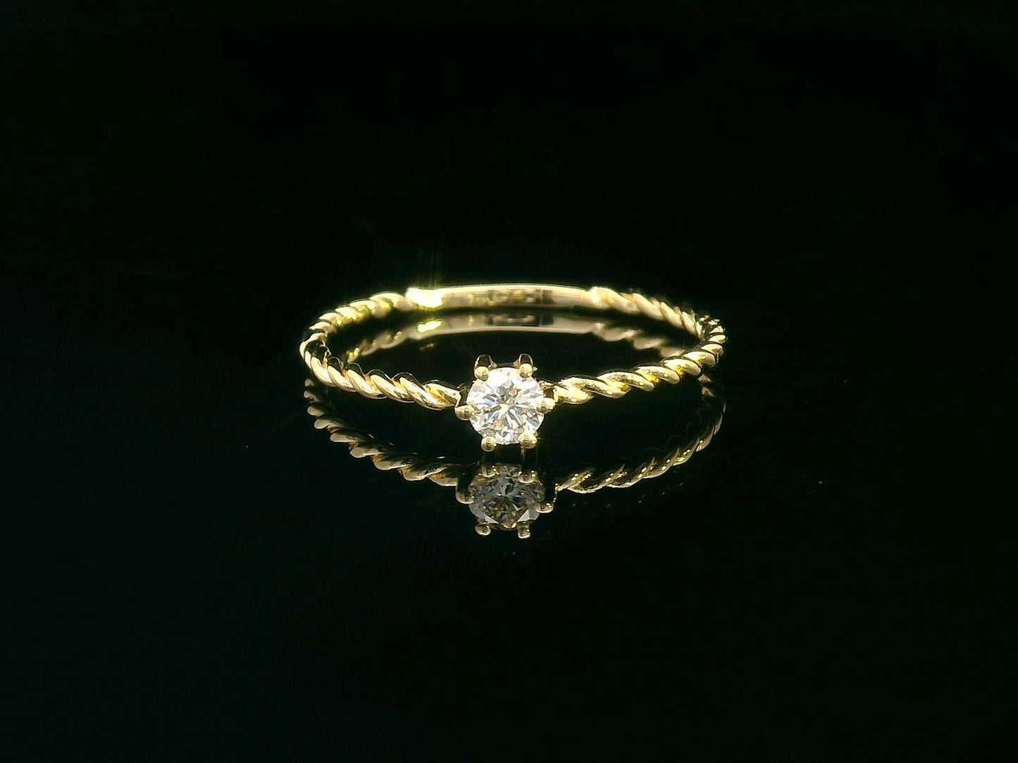 18K yellow gold twisted band diamond ring featuring a 0.15-carat round solitaire diamond in a delicate rope-style design