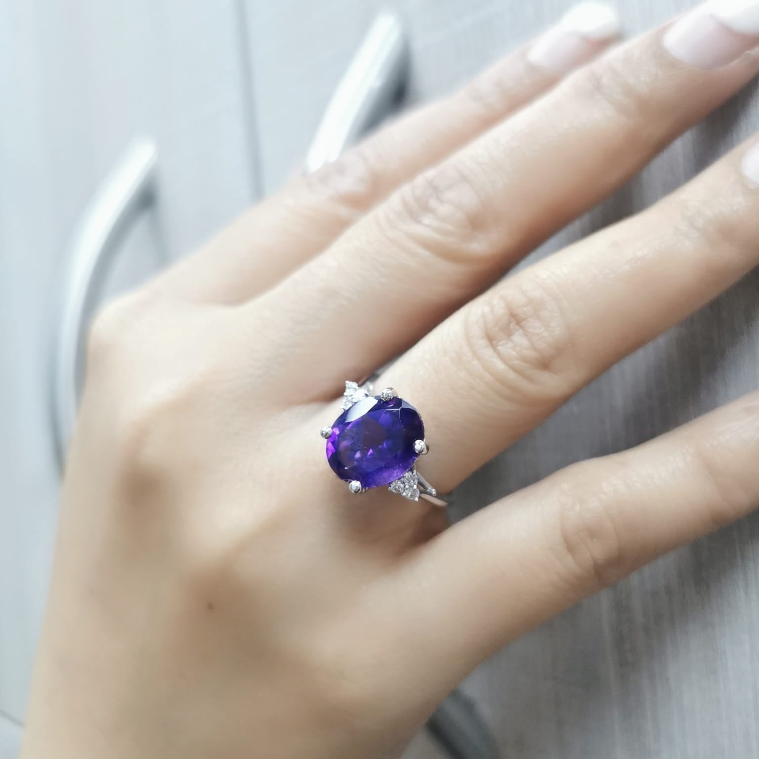 18K gold ring featuring a 4.37-carat oval-cut amethyst, accented by 0.13 carats of round diamonds.