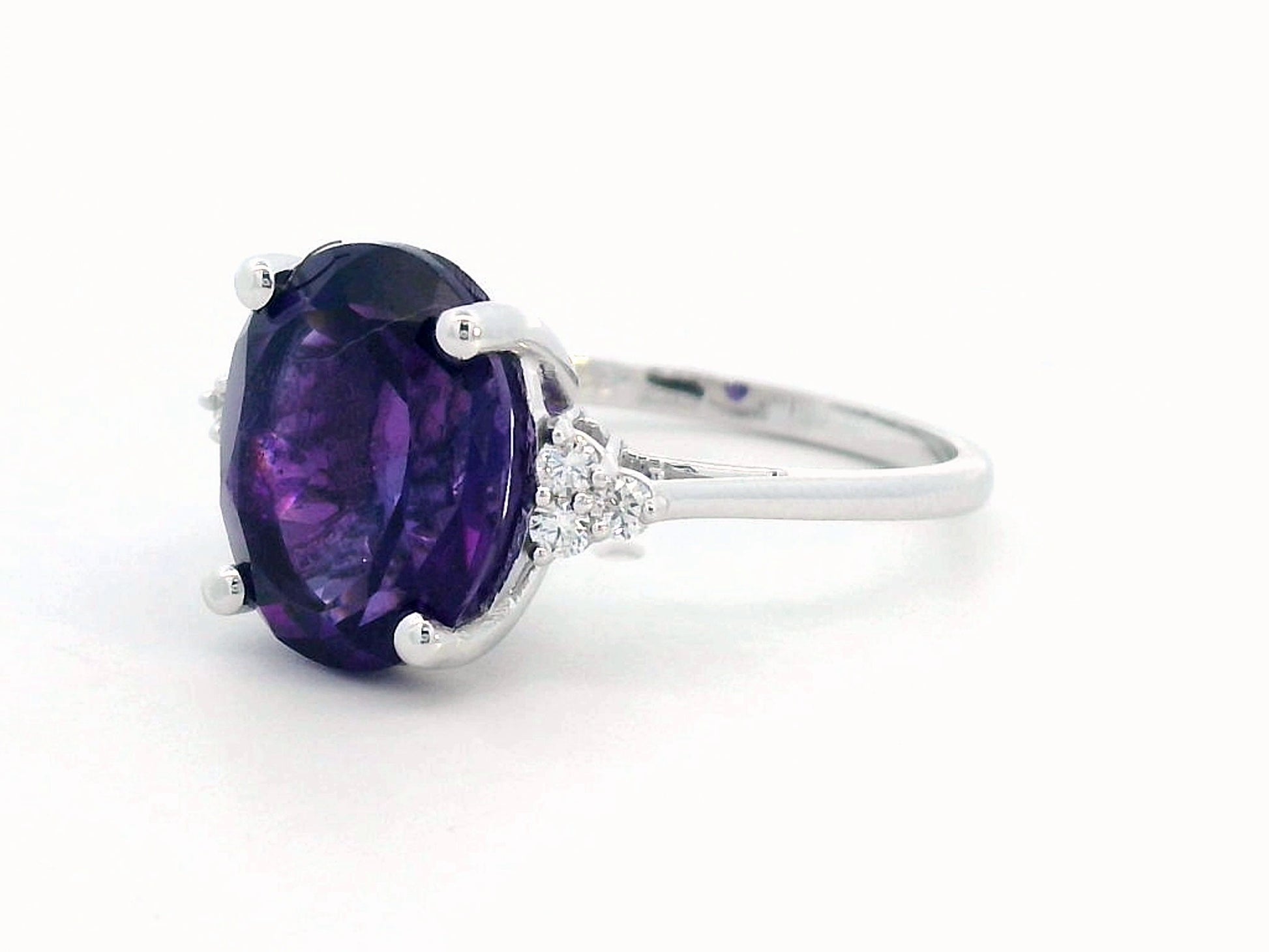 18K gold ring featuring a 4.37-carat oval-cut amethyst, accented by 0.13 carats of round diamonds.