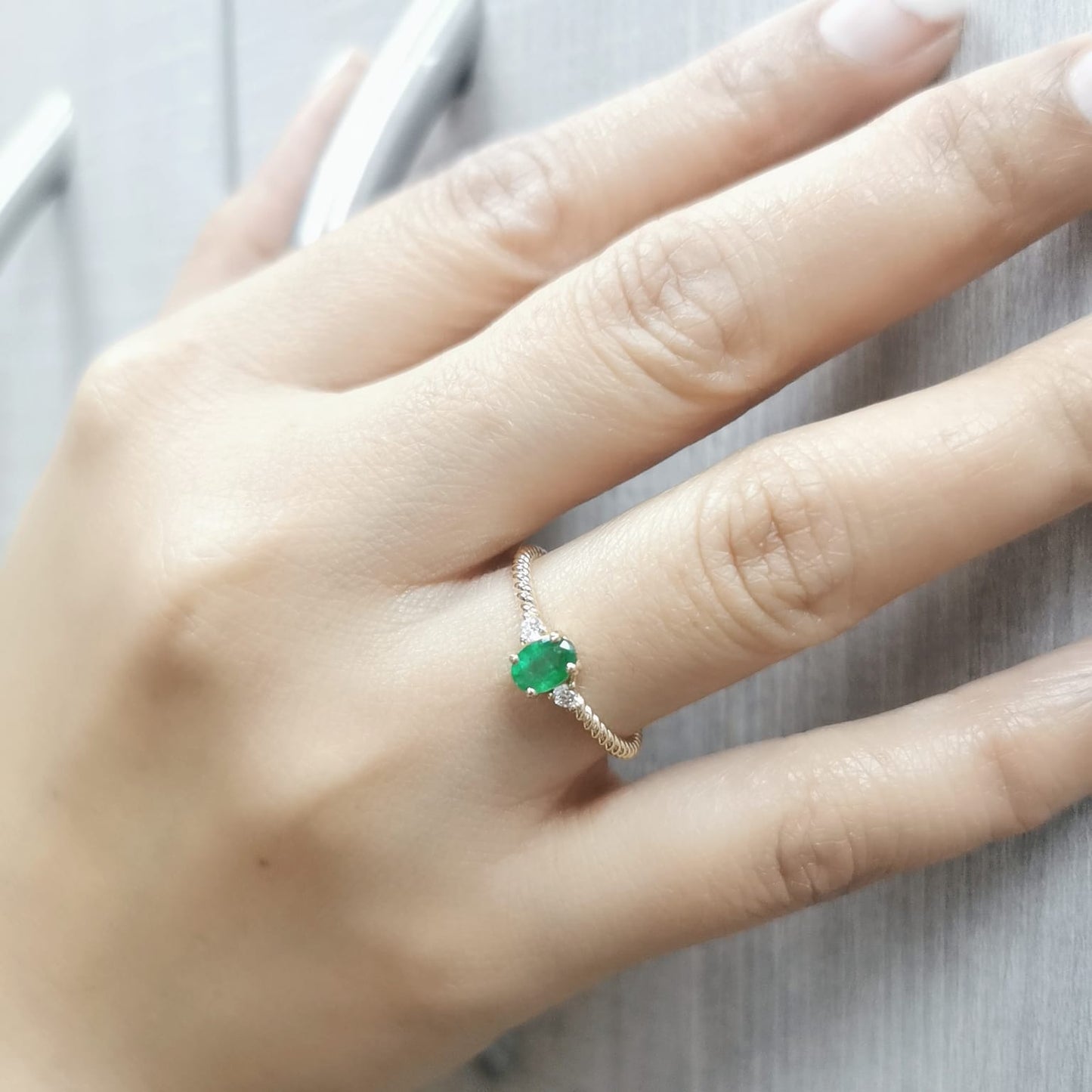18K gold twisted band emerald and diamond ring featuring a 0.44-carat oval emerald and 0.07-carat diamonds – perfect for stacking, engagement, or as a May birthstone ring