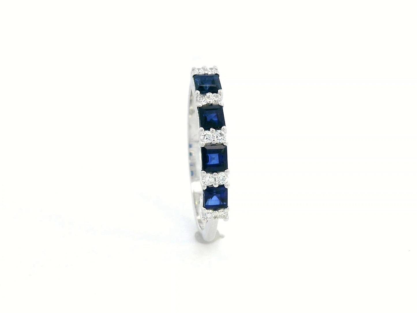 18K white gold sapphire and diamond eternity ring featuring princess-cut blue sapphires and round white diamonds in a half-eternity design.