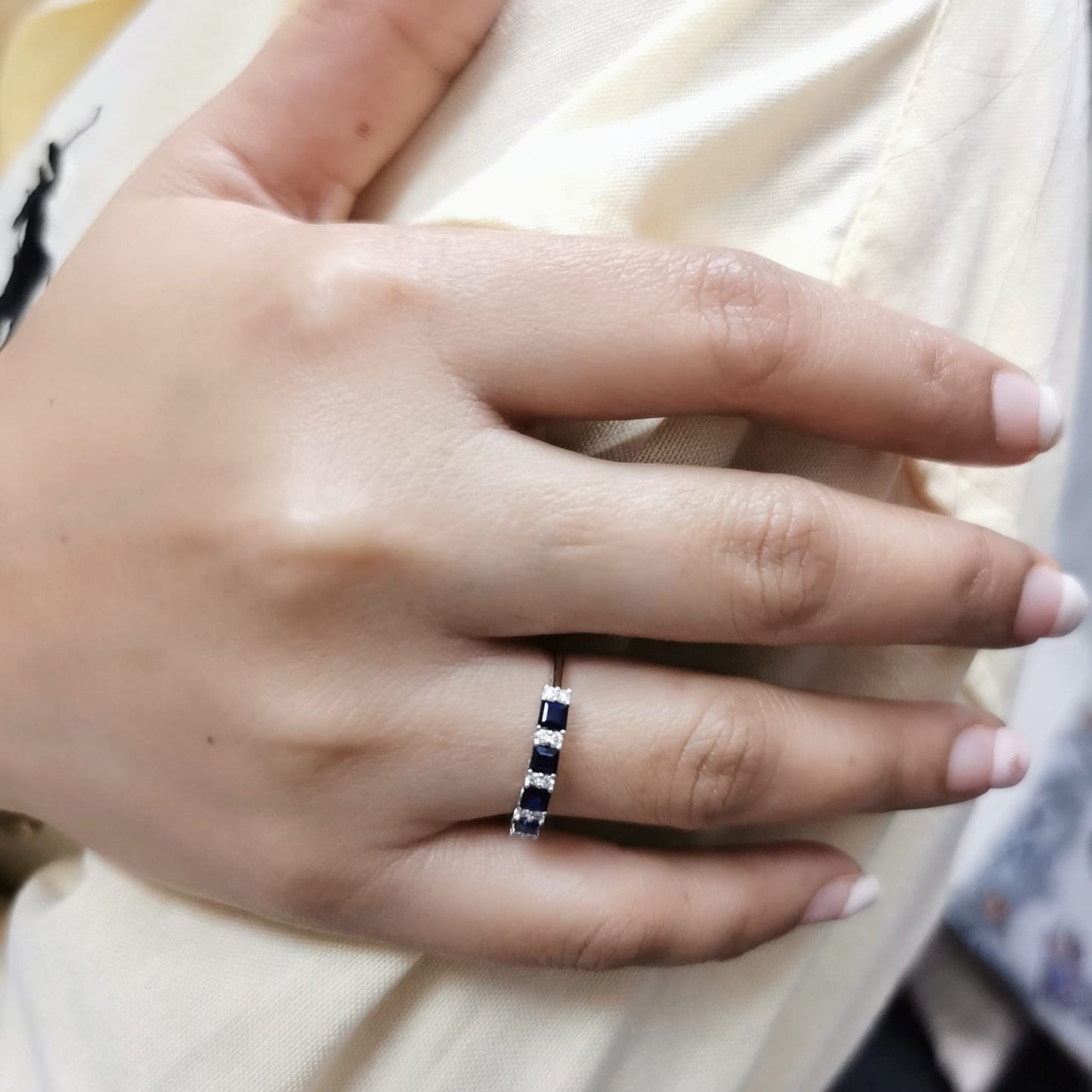 18K white gold sapphire and diamond eternity ring featuring square-cut blue sapphires and round white diamonds in a half-eternity design.