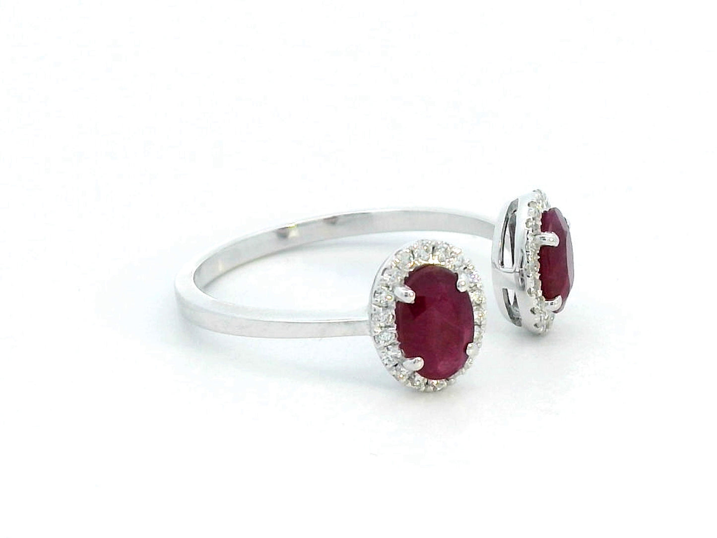 Elegant 18K gold bypass ring featuring two 1.07-carat oval rubies, accented by 0.17 carats of diamonds in a halo setting. A timeless statement piece