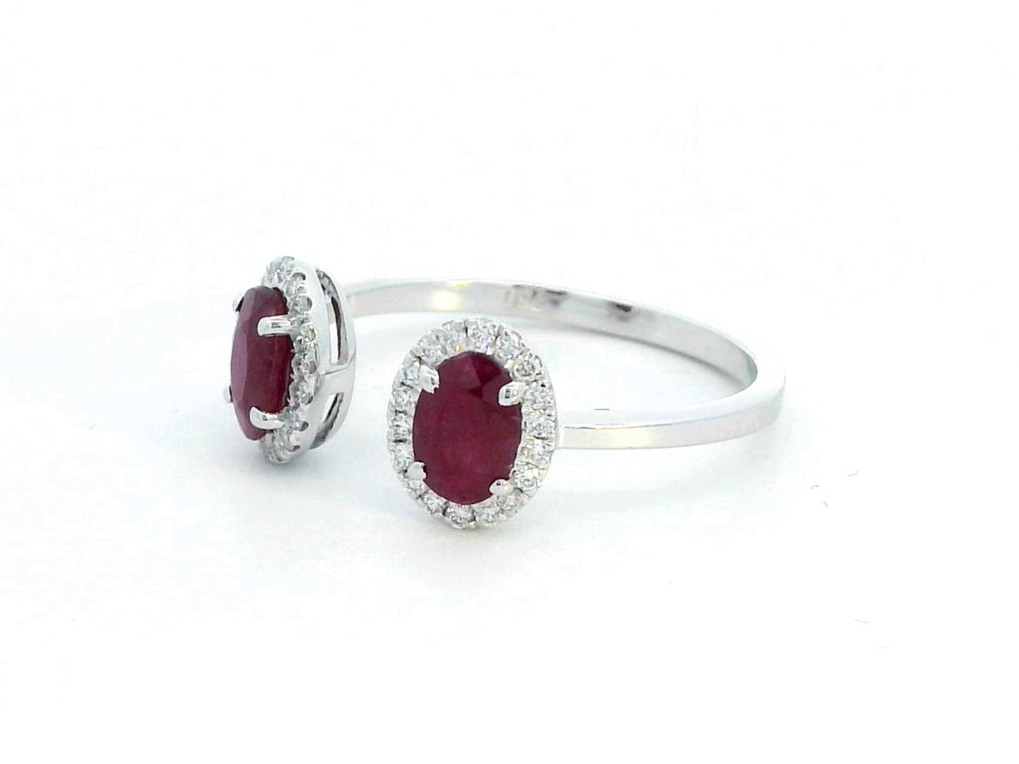 Elegant 18K gold bypass ring featuring two 1.07-carat oval rubies, accented by 0.17 carats of diamonds in a halo setting. A timeless statement piece