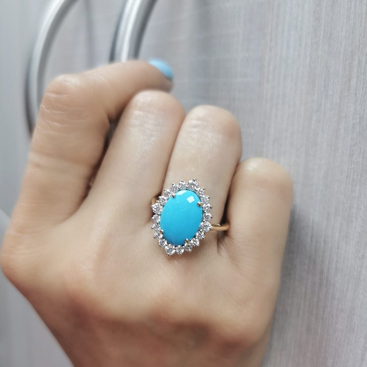 Elegant 18K gold ring featuring a 2.86-carat oval turquoise center stone, surrounded by a sparkling 0.69-carat diamond halo. A timeless statement piece.