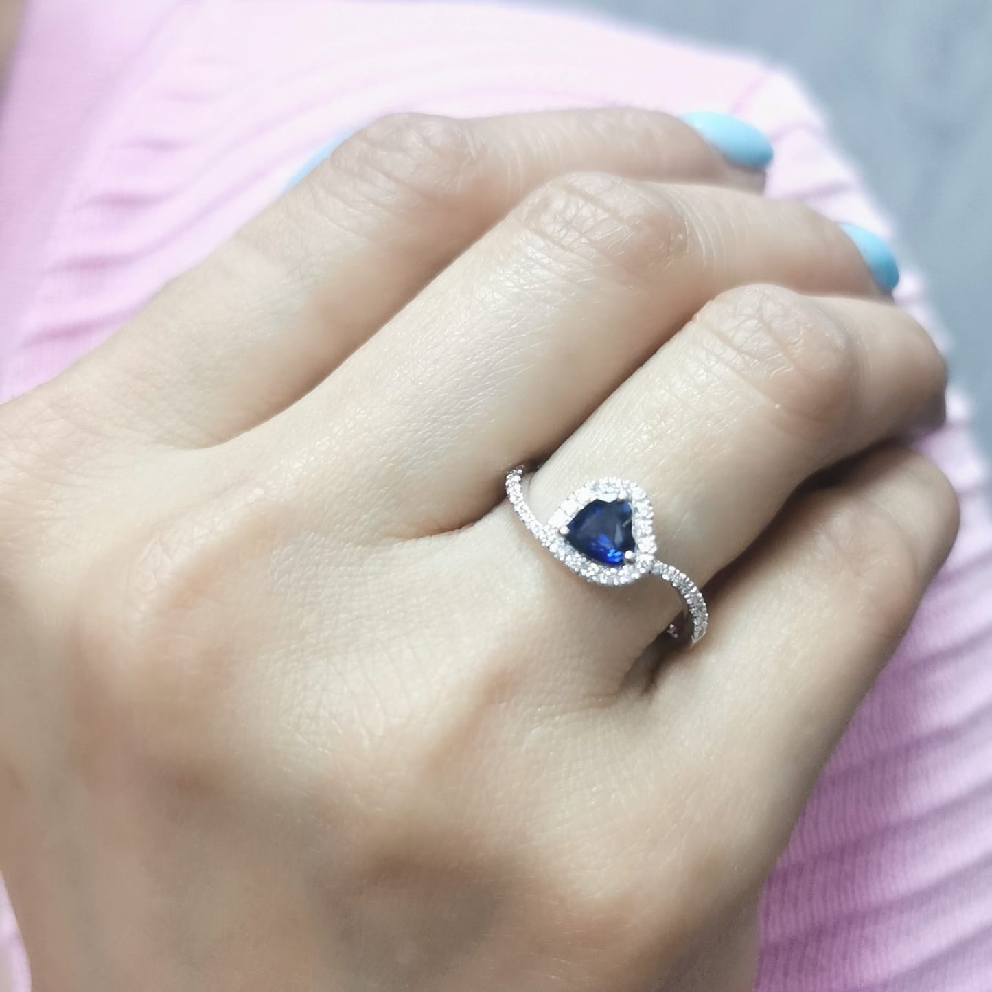 Heart-cut blue sapphire ring with diamond halo set in 18K gold, featuring a bypass design for a romantic touch.