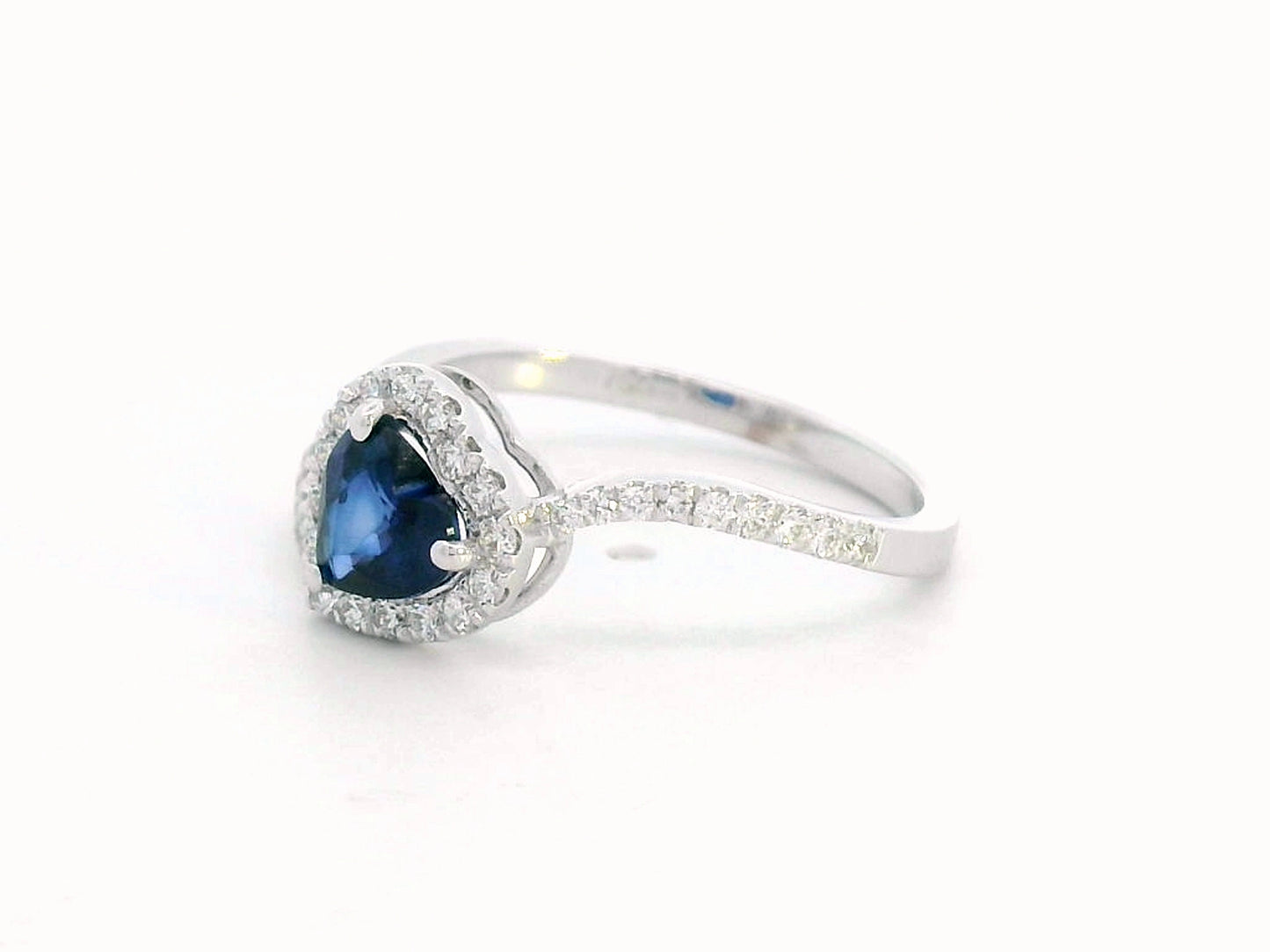 Heart-cut blue sapphire ring with diamond halo set in 18K gold, featuring a bypass design for a romantic touch.