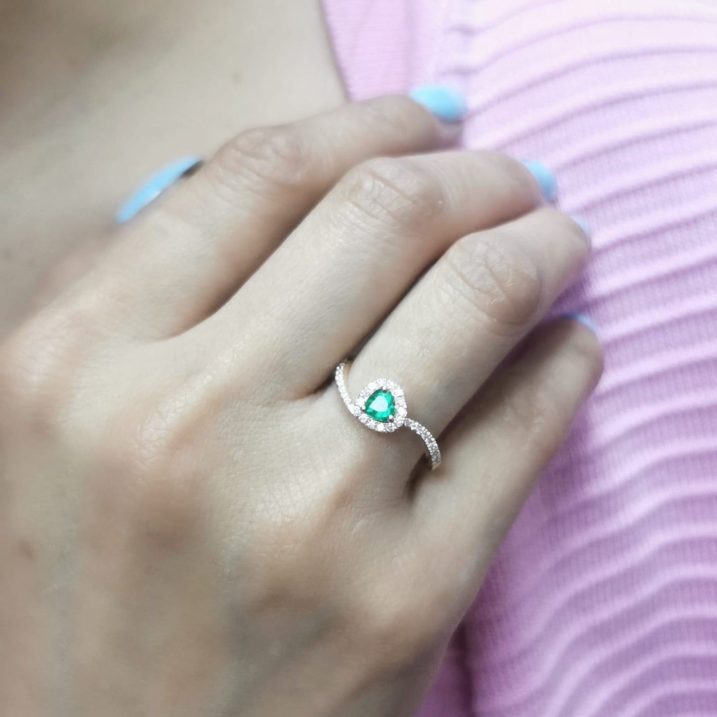 Heart-cut emerald ring with a diamond halo in 18K gold, featuring a bypass design for a timeless and elegant look.