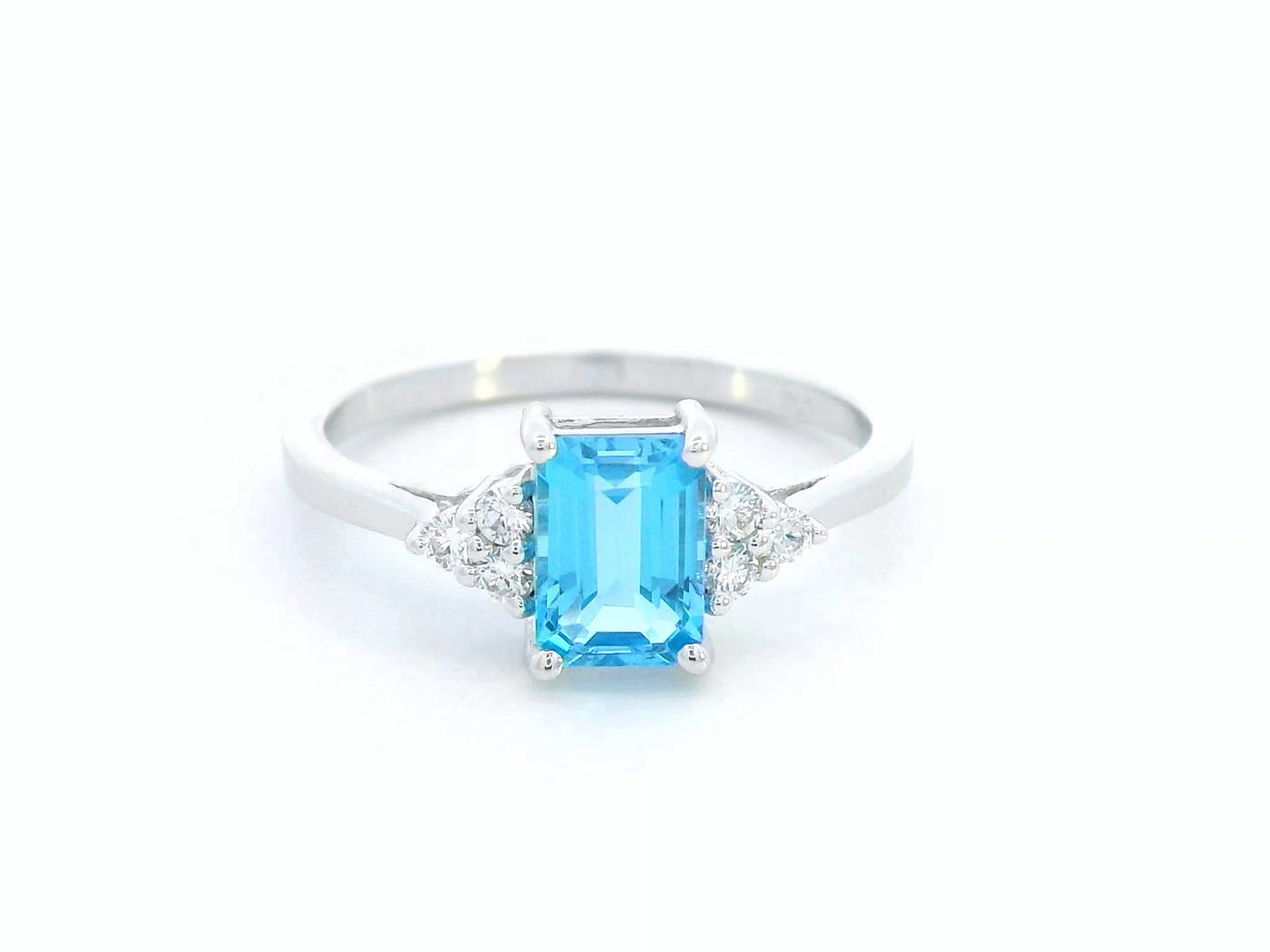 18K white gold ring with emerald-cut blue topaz and side diamond clusters – modern blue gemstone cocktail ring