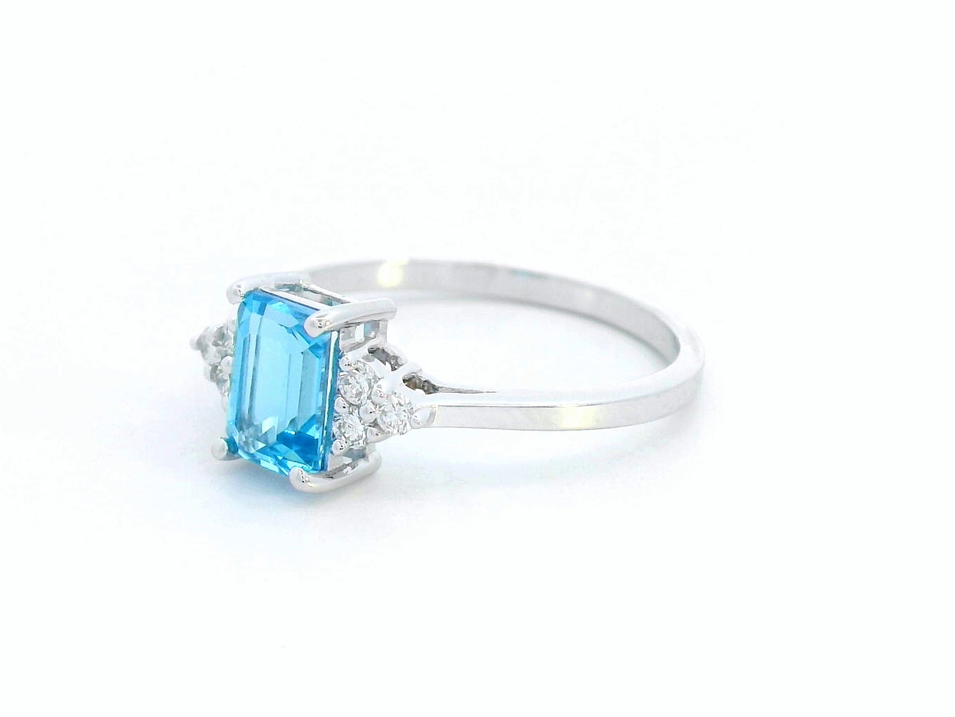 18K white gold ring with emerald-cut blue topaz and side diamond clusters – modern blue gemstone cocktail ring