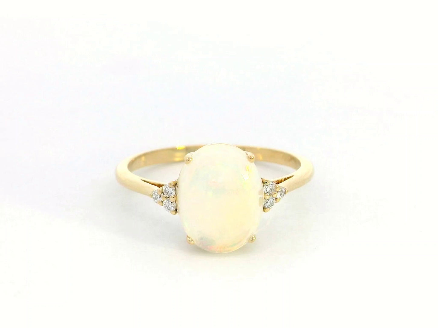 18K yellow gold ring with oval opal center flanked by accent diamonds.