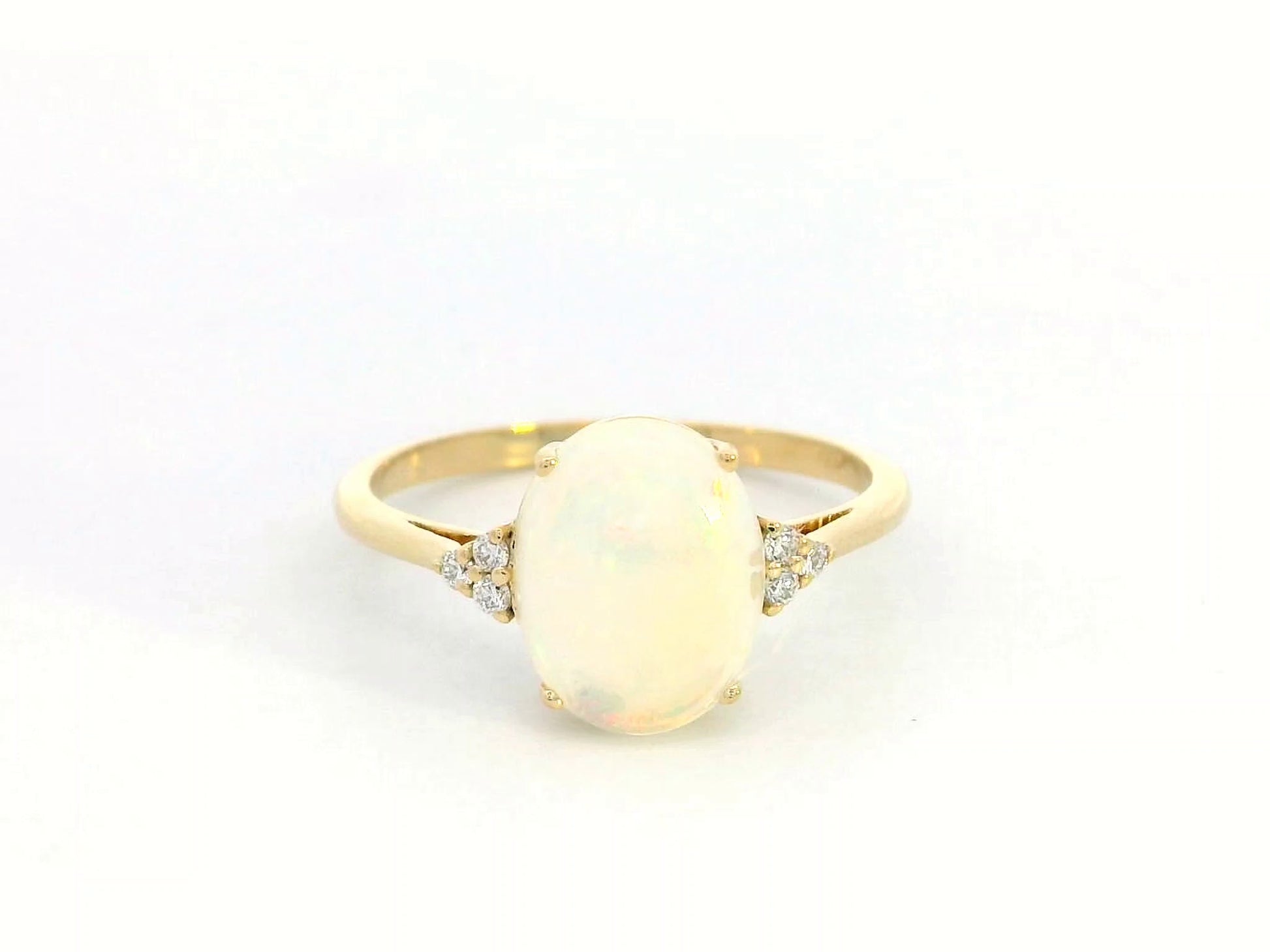 18K yellow gold ring with oval opal center flanked by accent diamonds.