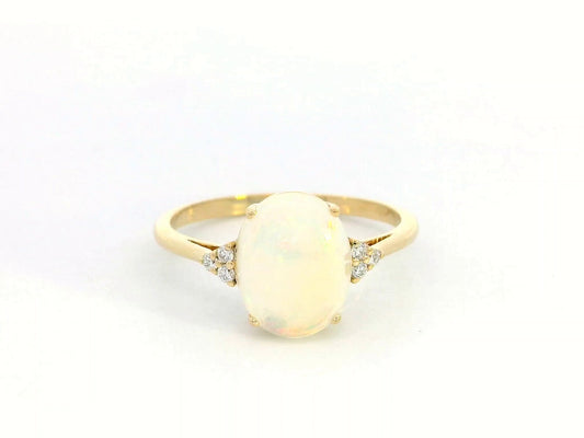 18K yellow gold ring with oval opal center flanked by accent diamonds.