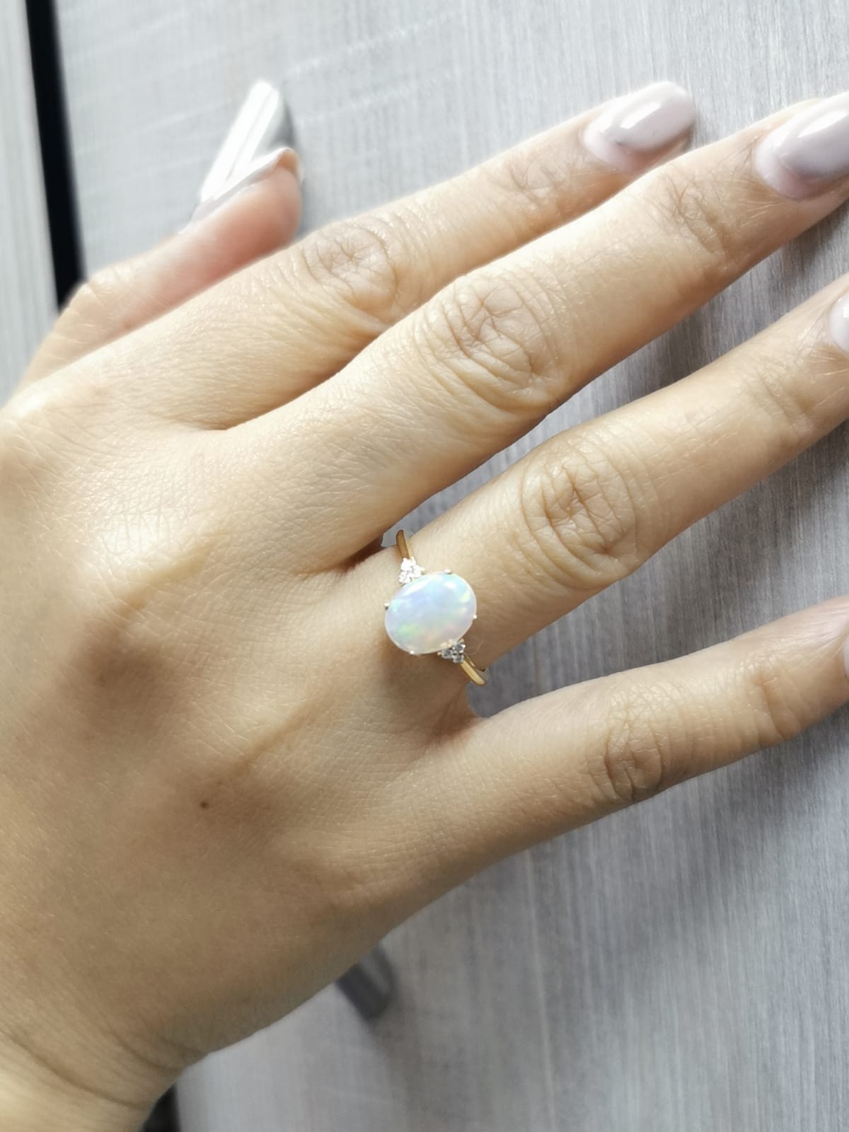 18K yellow gold ring with oval opal center flanked by accent diamonds.