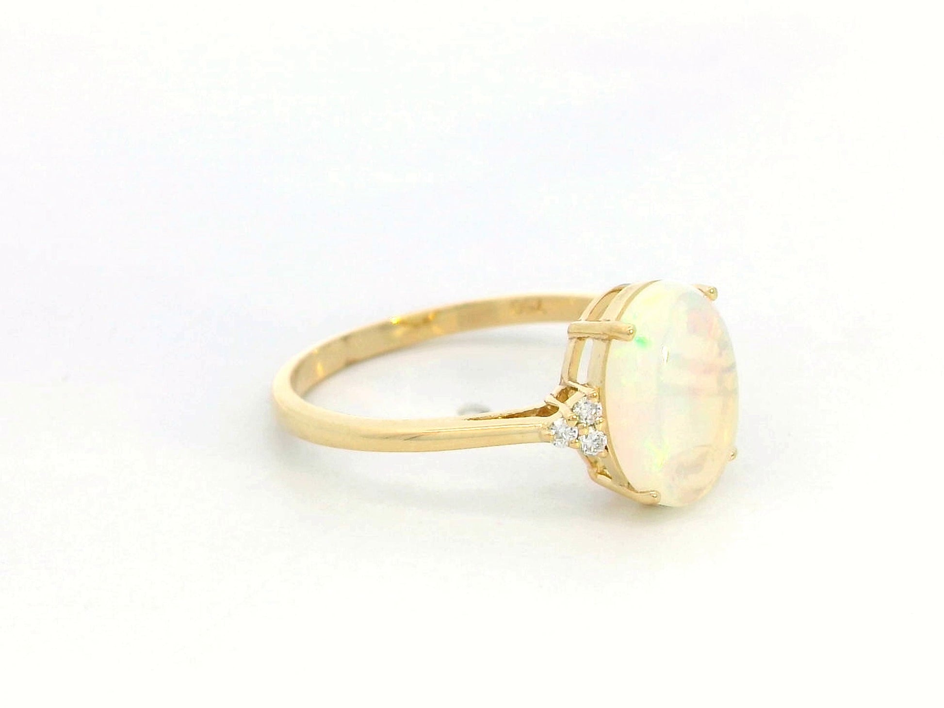 18K yellow gold ring with oval opal center flanked by accent diamonds.