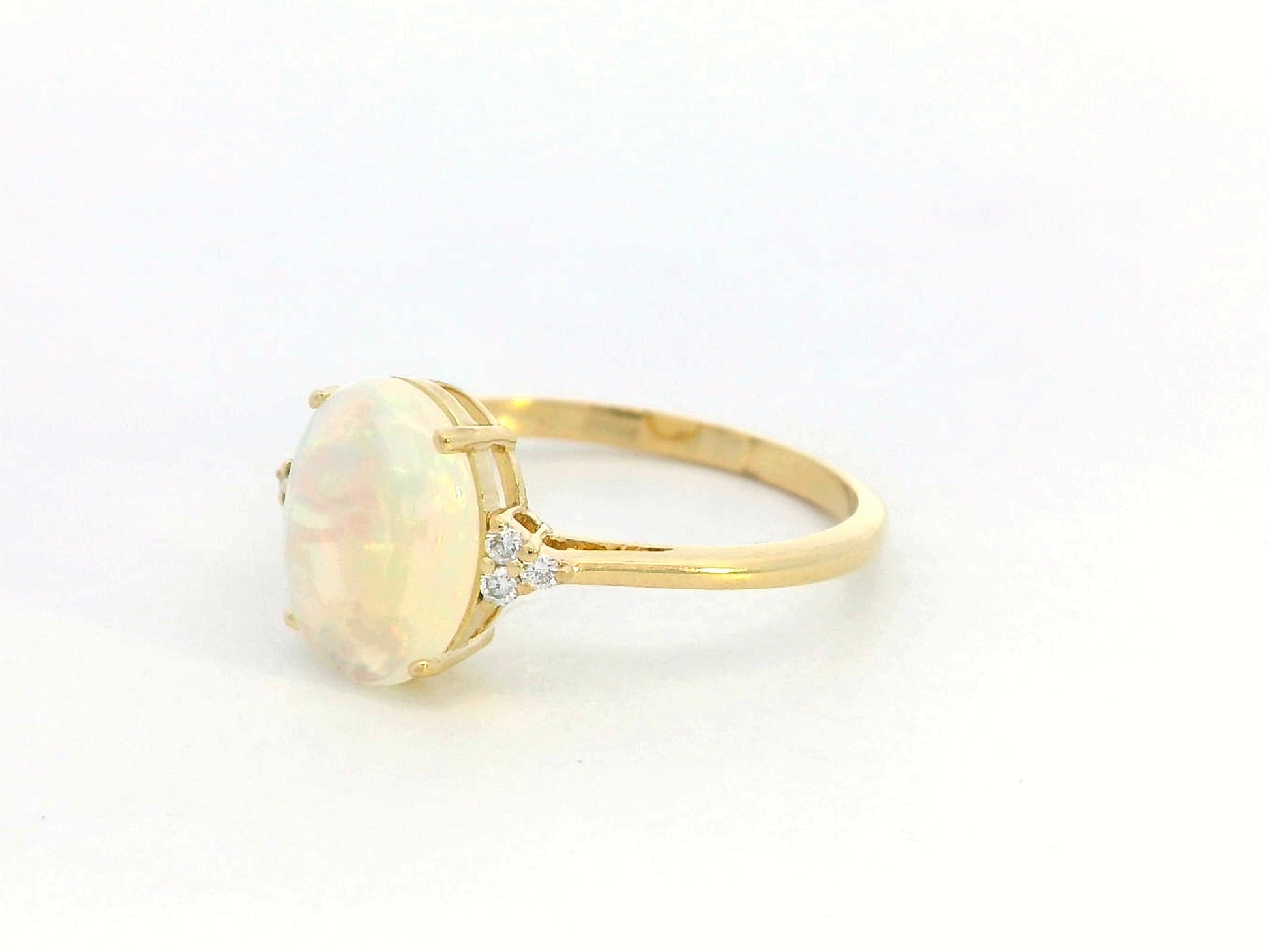 18K yellow gold ring with oval opal center flanked by accent diamonds.