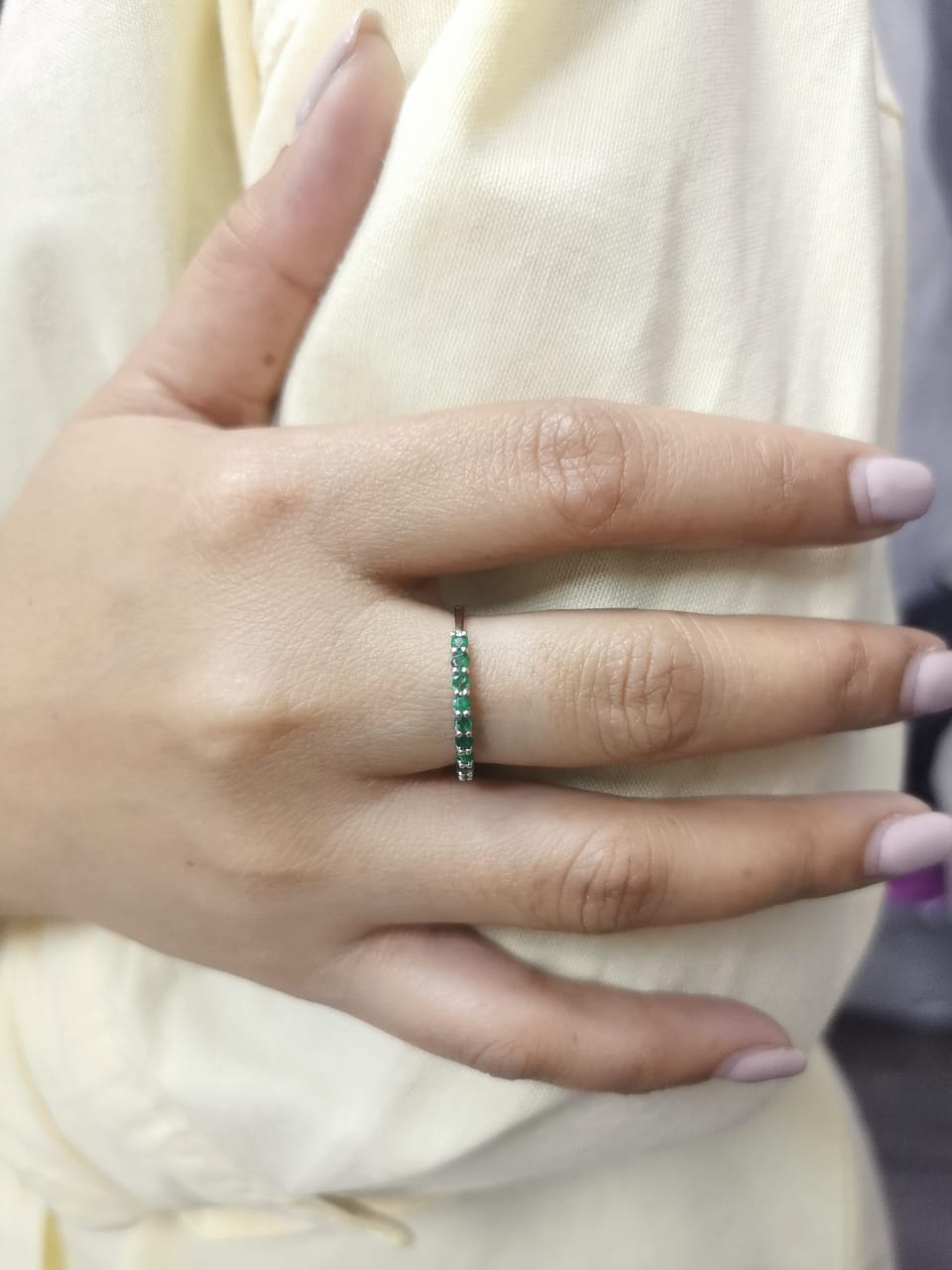 18K gold half-eternity ring with 0.42 carat round-cut emeralds in a prong setting.